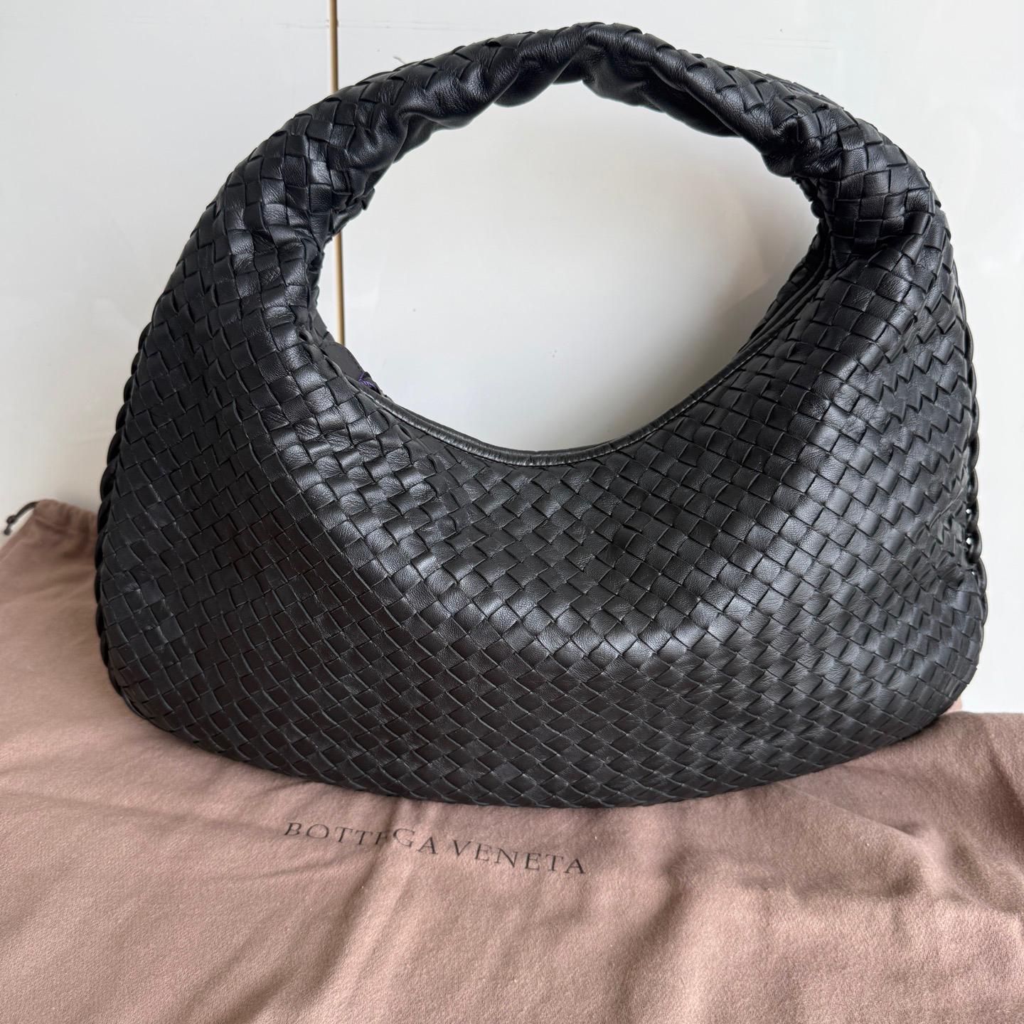 Este Bolso Hobo Bottega Veneta es una pieza excepcional de lujo, fabricada en la emblemática piel de cordero negra con el tejido Intrecciato, reconocible al instante. Con espacio suficiente para todo lo que necesitas, es el accesorio de invierno
