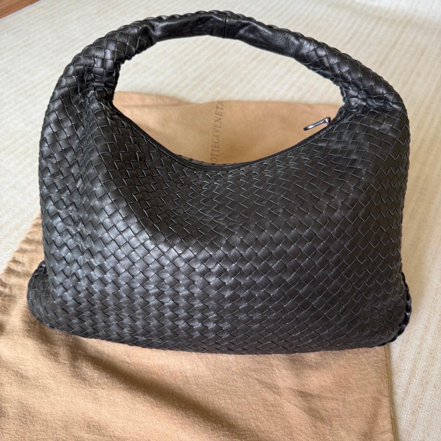 Questa borsa Hobo di Bottega Veneta è un pezzo di lusso eccezionale, realizzato con l'iconica pelle d'agnello nera con l'inconfondibile trama Intrecciato. Abbastanza capiente da contenere tutti i tuoi oggetti essenziali, è l'accessorio invernale