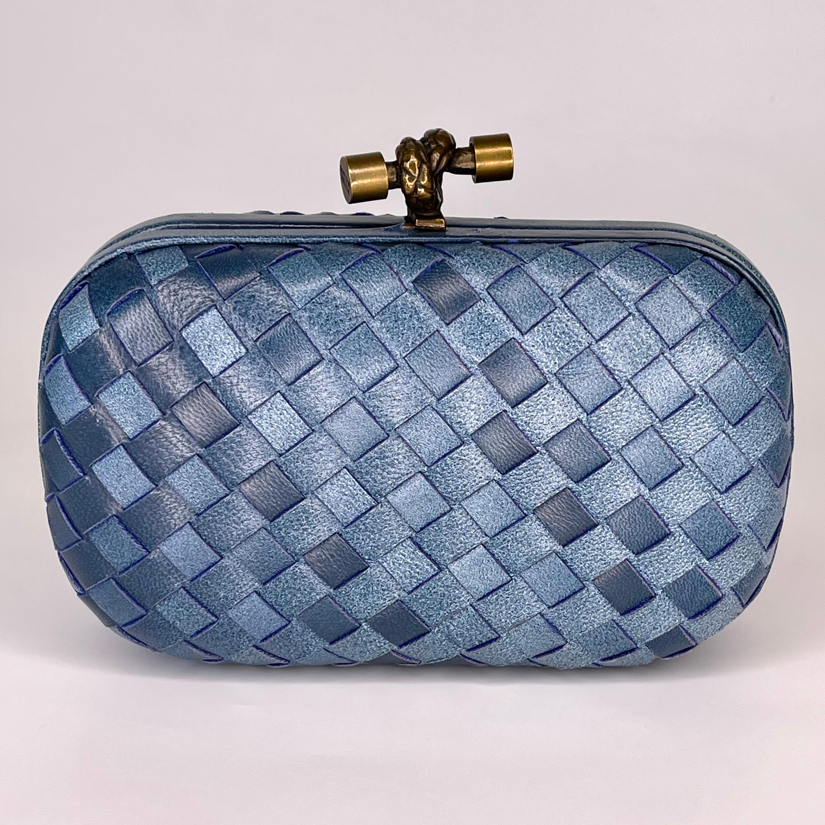 Diese Tasche ist aus blauem Intrecciato-Leder gefertigt und verfügt über einen goldfarbenen Knoten an der Oberseite mit Druck-/Riegelverschluss. Innenfutter aus braunem Satin. Perfekt:: um Ihre Karten und Schlüssel beim Abendessen aufzubewahren.