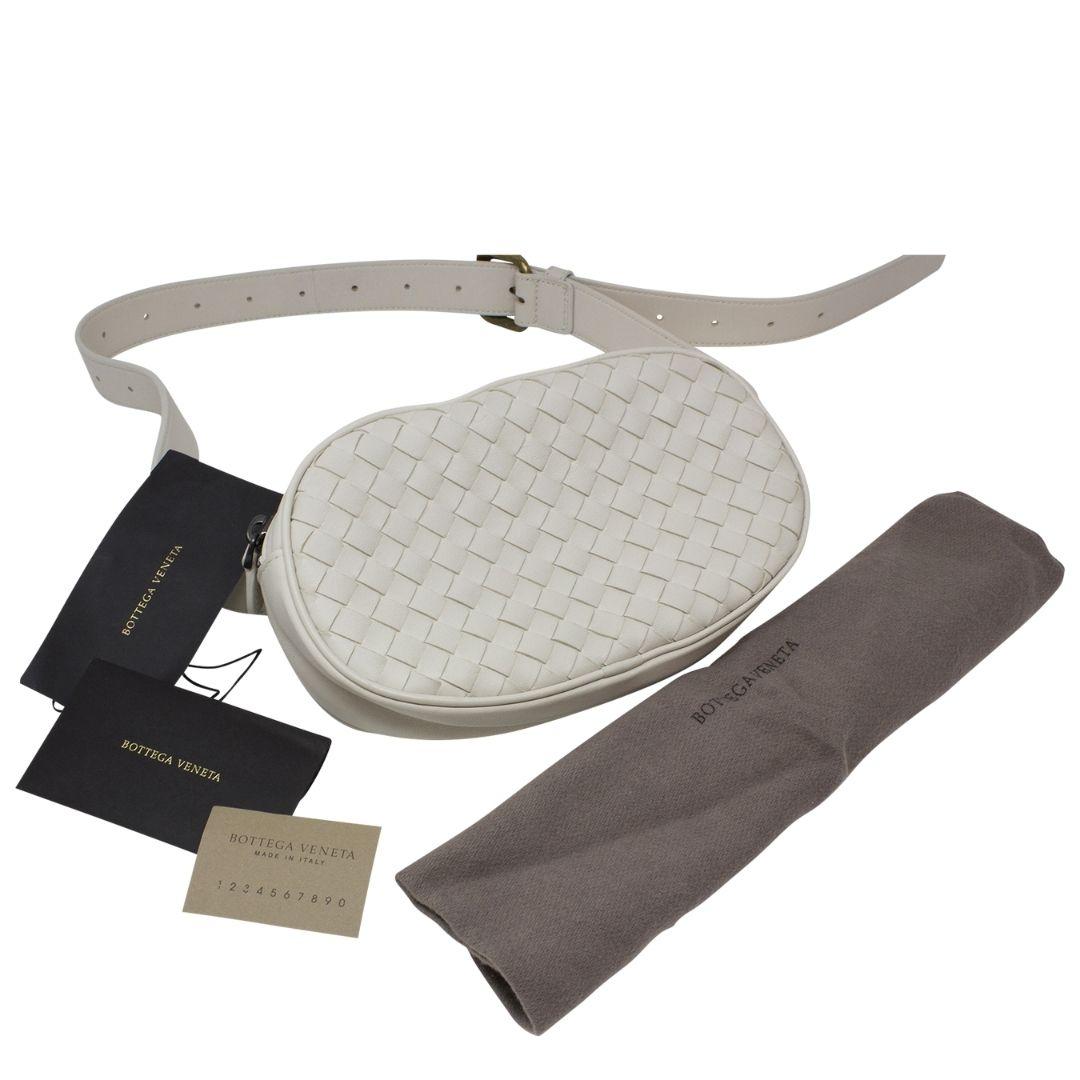 Gorgeous Bottega by Tomas Maier to bring along with you when you are running errands or pushing your stroller on your hot girl walk! Crafted in white intrecciato leather, with an adjustable crossbody/waist strap and gunmetal hardware. The zipper