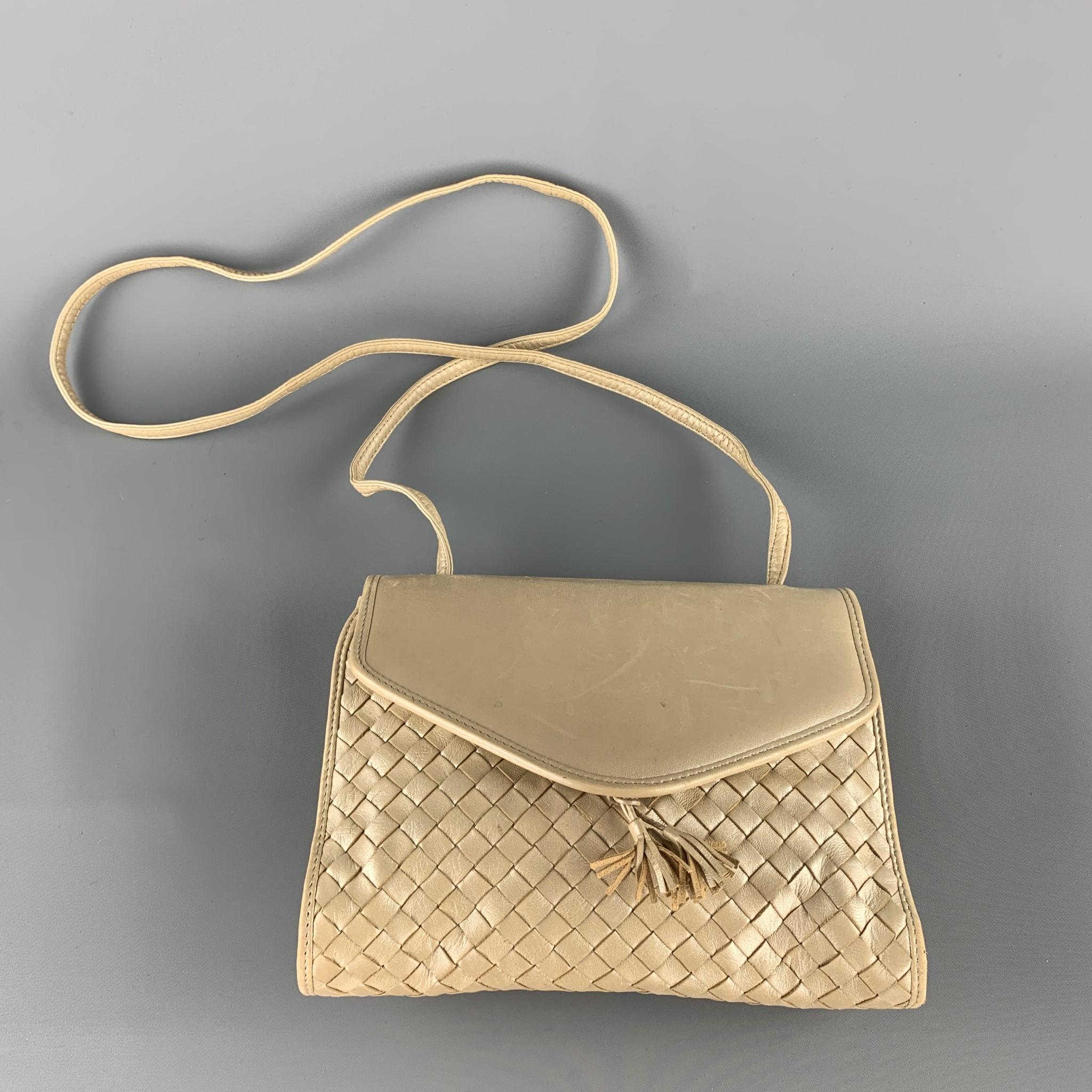 Vintage BOTTEGA VENETA bag comes in metallic champagne woven intrecciato leather with a smooth snap top flap, tassel accents, skinny strap, and leather interior. Made in Italy.

Very Good Pre-Owned Condition.

Measurements:

Length: 9 in.
Width: 2