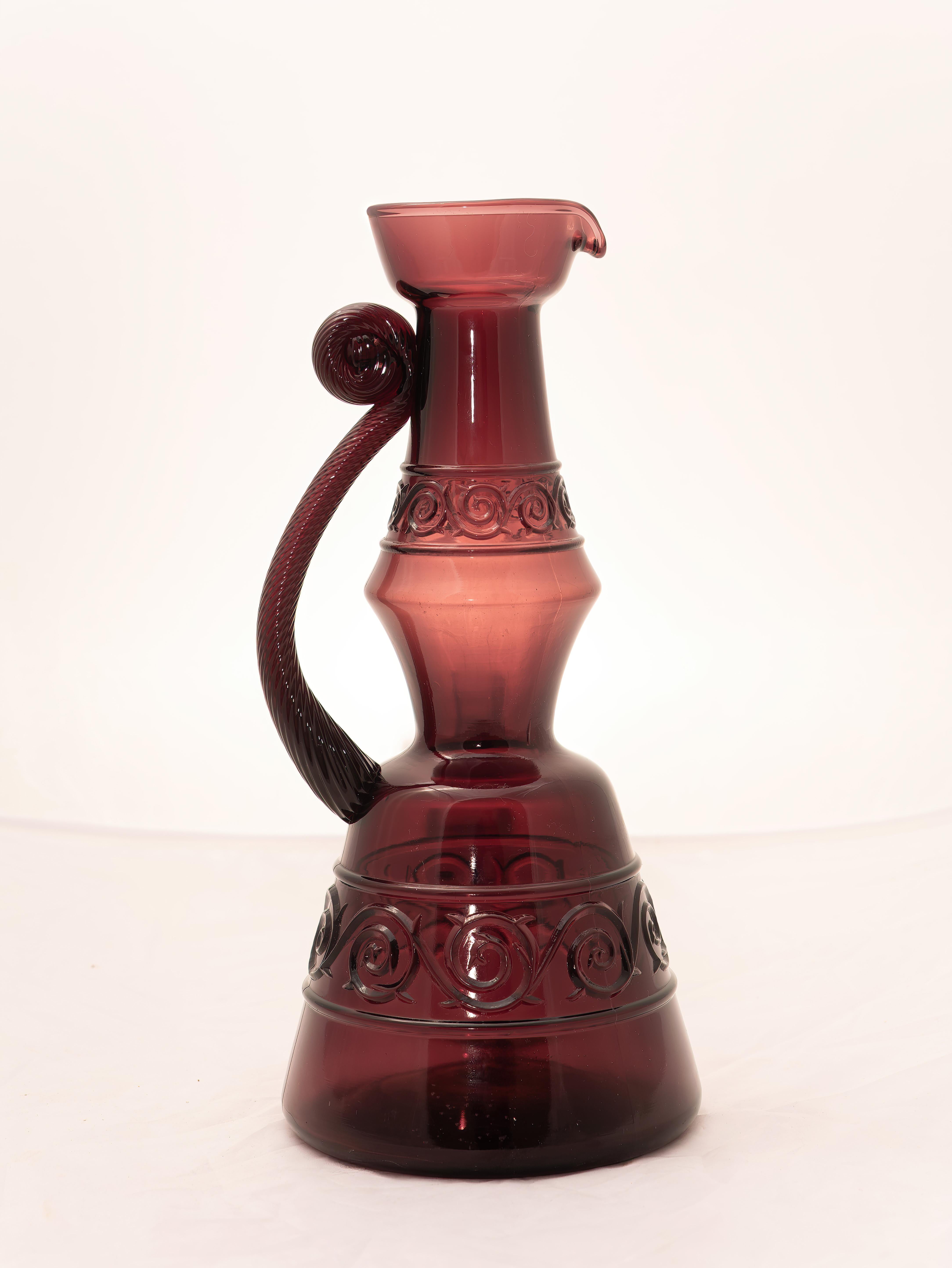 Lila Glasflasche (Dekanter), hergestellt in Italien, 1960er Jahre. 
Hübsche lilafarbene Karaffe mit eingravierten Designkreationen. Der Griff hat eine ganz besondere Verarbeitung, die ihn einzigartig macht. Es ist ein schönes Objekt, das in jede
