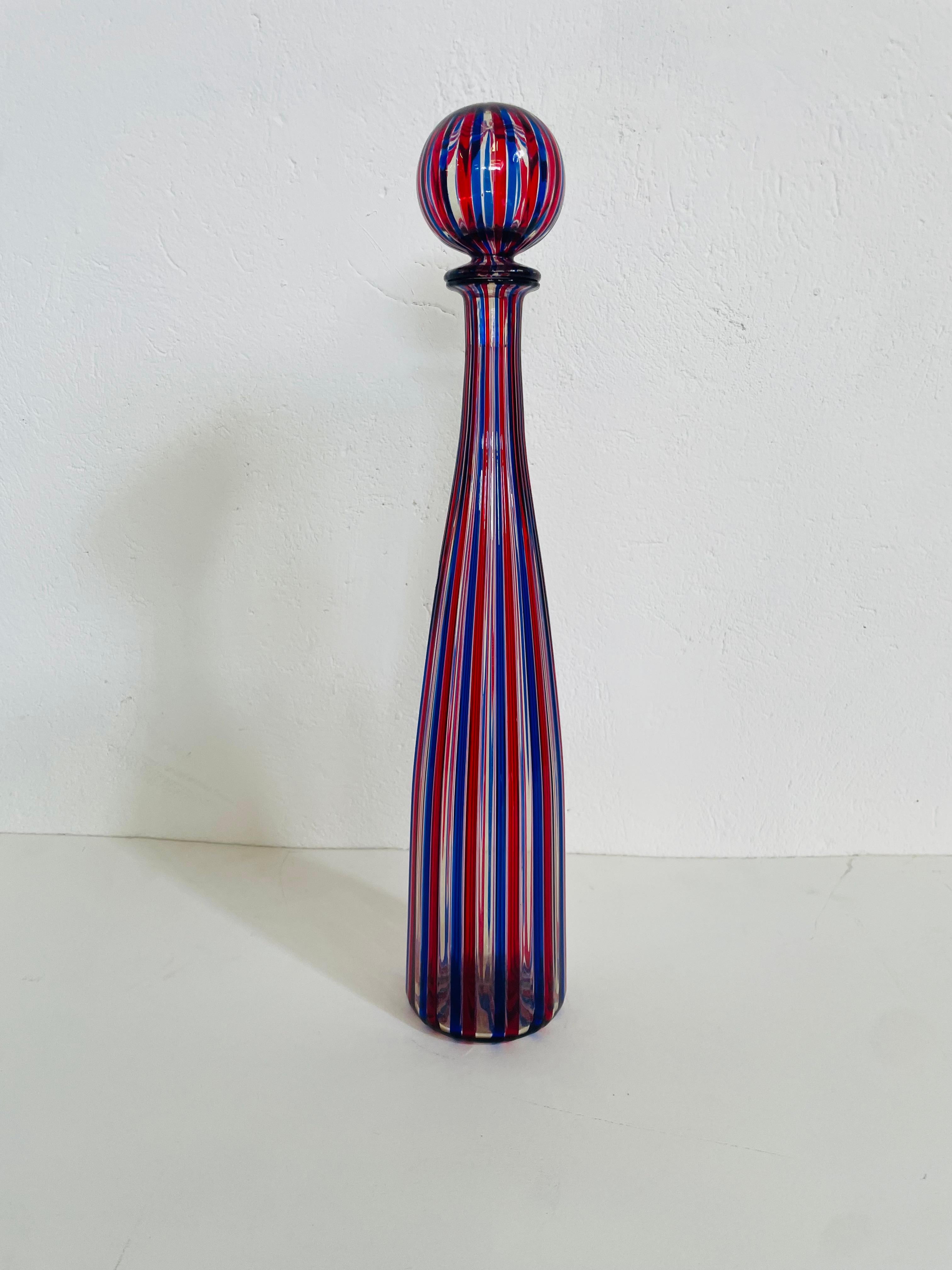 Questa elegante e raffinata bottiglia del 1989 in vetro di Murano di Venini, è ispirata dai dipinti di Giorgio Morandi. Ideata nel 1956 dall’Avv. Paolo Venini è stata realizzata con la collaborazione del grande Architetto Gio’ Ponti. E’ in vetro