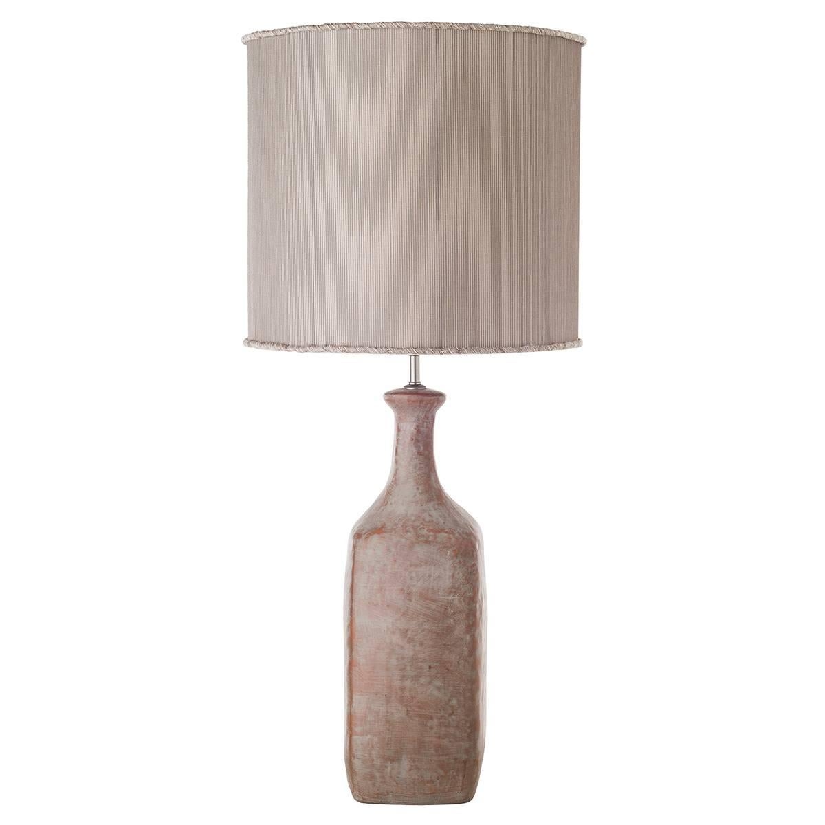 Bottle-shaped ceramic table lamps with shades.

The body of the lamps is characterized by a bottle shape and is decorated with a refined grey-stone patina. The table lamps are completed by a cylindrical shade in sand color. Warm hues make them