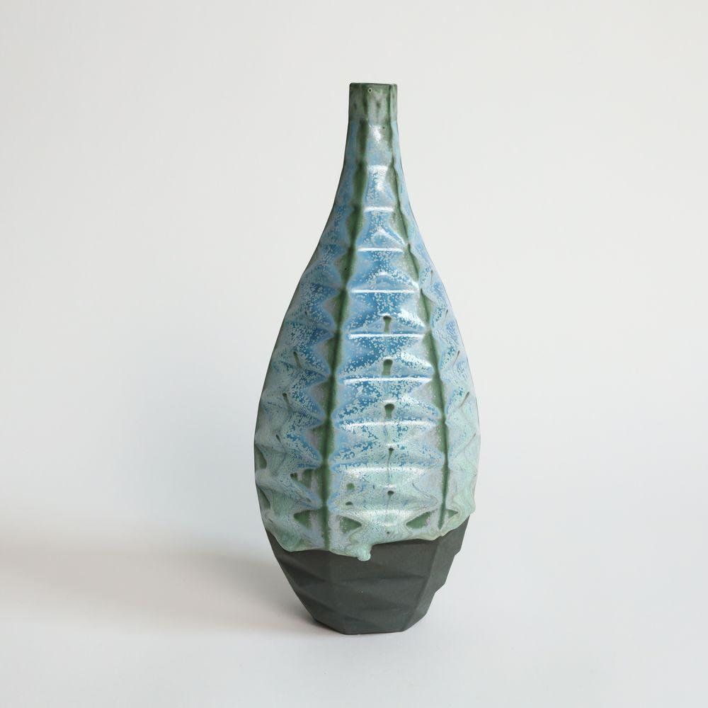 Bottle Patterned Vessel in Lime Moondust
Introducing the Bottle Patterned Vessel, a beautiful and contemporary piece of art that seamlessly blends traditional craftsmanship with modern design. This stunning vase features an intricate pattern that