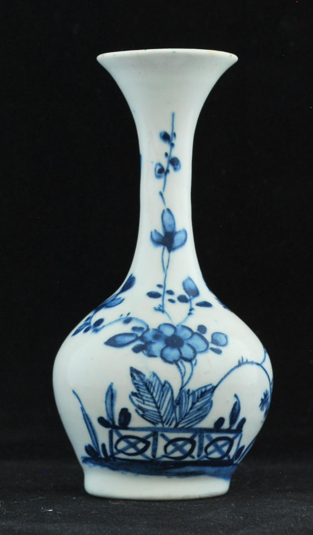 Bottle, circa 1746-1748: Small thrown bottle vase of bulbous form with elongated neck and flaring trumpet top. Somewhat primitively painted in tones of a ‘sooty’ blue underglaze with a rambling plant rising from behind a fence among leaves and