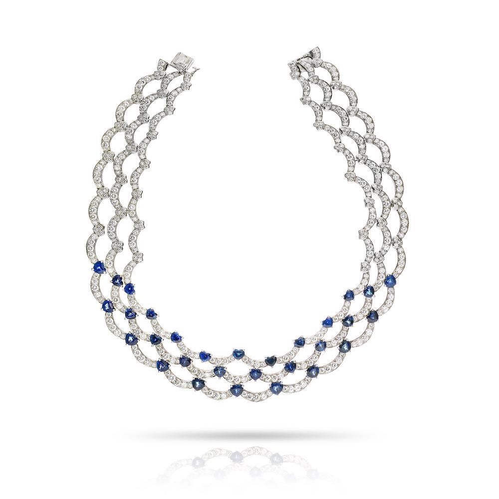 A SAPPHIRE AND DIAMOND NECKLACE AND EARRINGS SUITE, BY BOUCHERON.
Composed of a series of brilliant-cut diamonds and heart-cut blue sapphires, both necklace and earrings are designed as an open continuous triple wave pattern. 
Diamond Carat Weight: