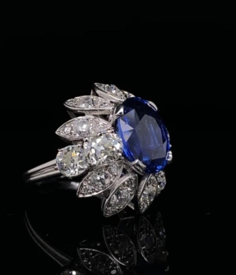 A Boucheron 4.90 carat sapphire and diamond cluster ring in platinum, circa 1950.

This exceptional ring is set to its centre with a stunning oval cut sapphire of 4.90 carat approximately.
The sapphire has a beautiful vibrant royal blue colour to it