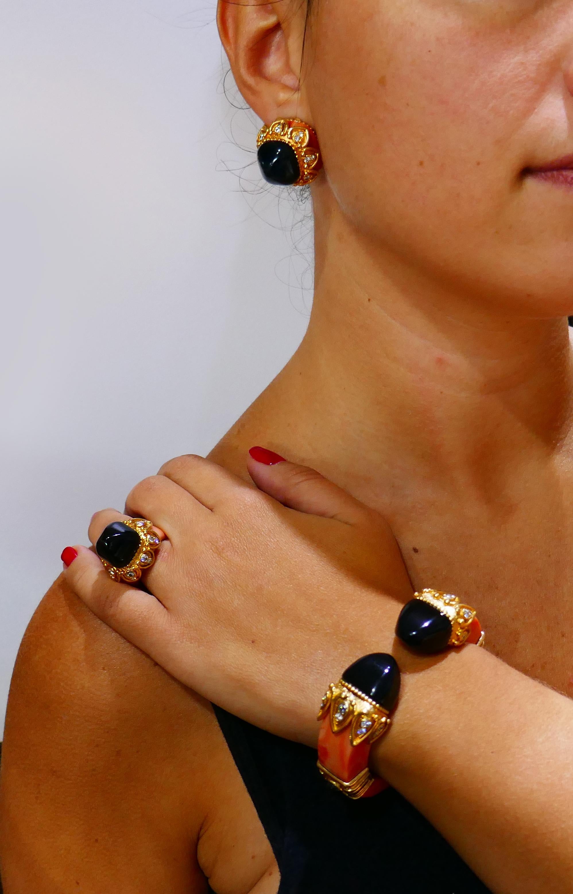 Fabulous vintage set consisting of a bangle bracelet, clip-on earrings and a ring created by Boucheron in Paris in the 1970s. 
The set is made of 18 karat yellow gold, coral, black onyx and sprinkled with round brilliant cut diamonds (G-H color, VS