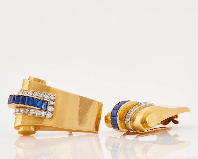 Important double clips in 18k yellow gold from the Retro period, ca. 1940s. These collectable clips were made by Boucheron Paris in a very dynamic design with sapphire baguettes and round brilliant cut diamonds. The clips are signed and numbered and