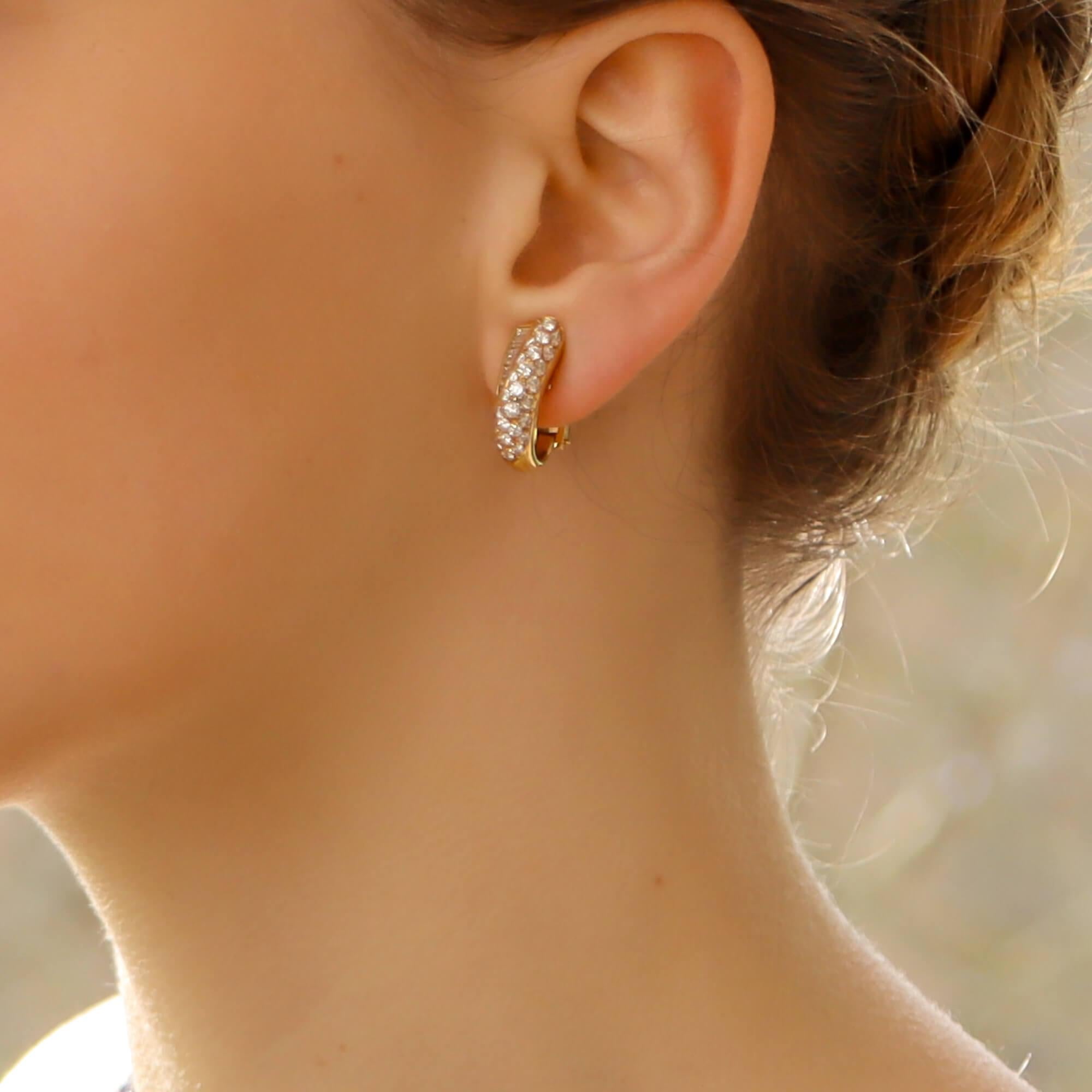 A pair of Boucheron diamond earrings in 18-karat yellow gold where each earring is designed as an elongated bombe-shaped hoop pave-set throughout with round brilliant-cut diamonds, accented with channel-set baguette-cut diamonds. 
The earrings are