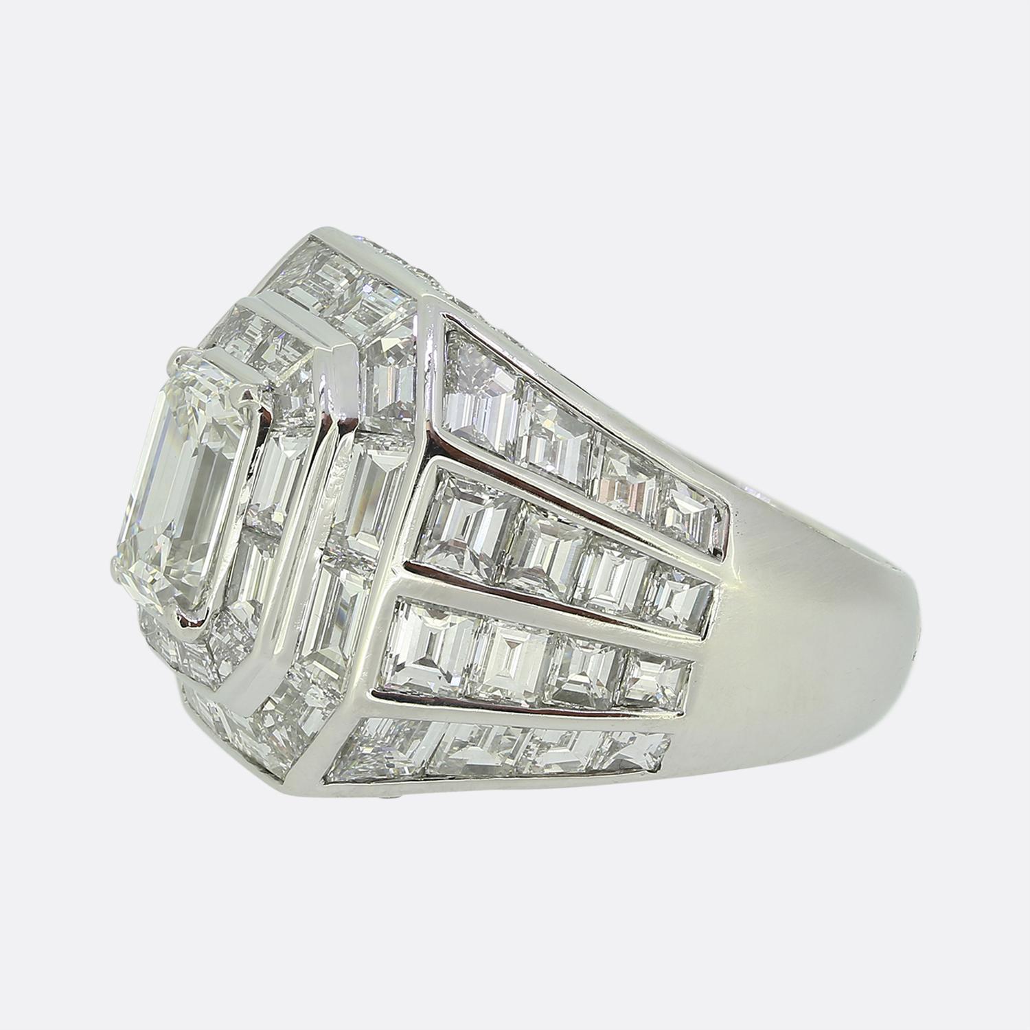 Here we have a sensational cocktail ring from the world renowned French jewellery house of Boucheron. This striking ring showcases a centralised emerald-cut diamond, expertly set to draw the eye. Surrounding this principal stone is a series of