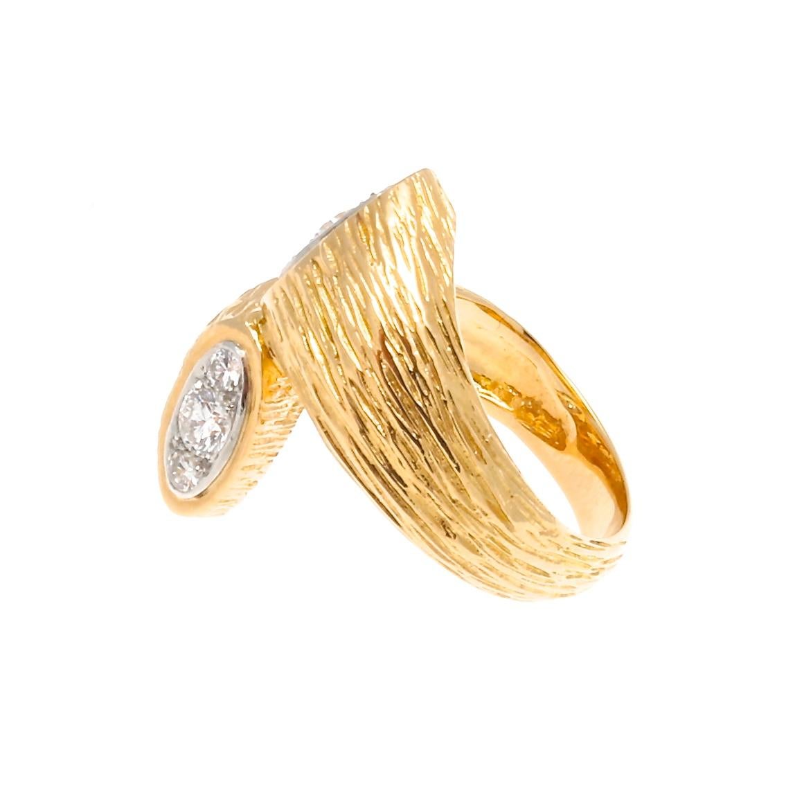 One of Boucheron's goals is to symbolically animate the inanimate. They have this by emphasizing the goldsmith work in their masonry. Featuring a textured 18k gold gold bypass ring ending in two diamond heads creating this motif. Signed Boucheron