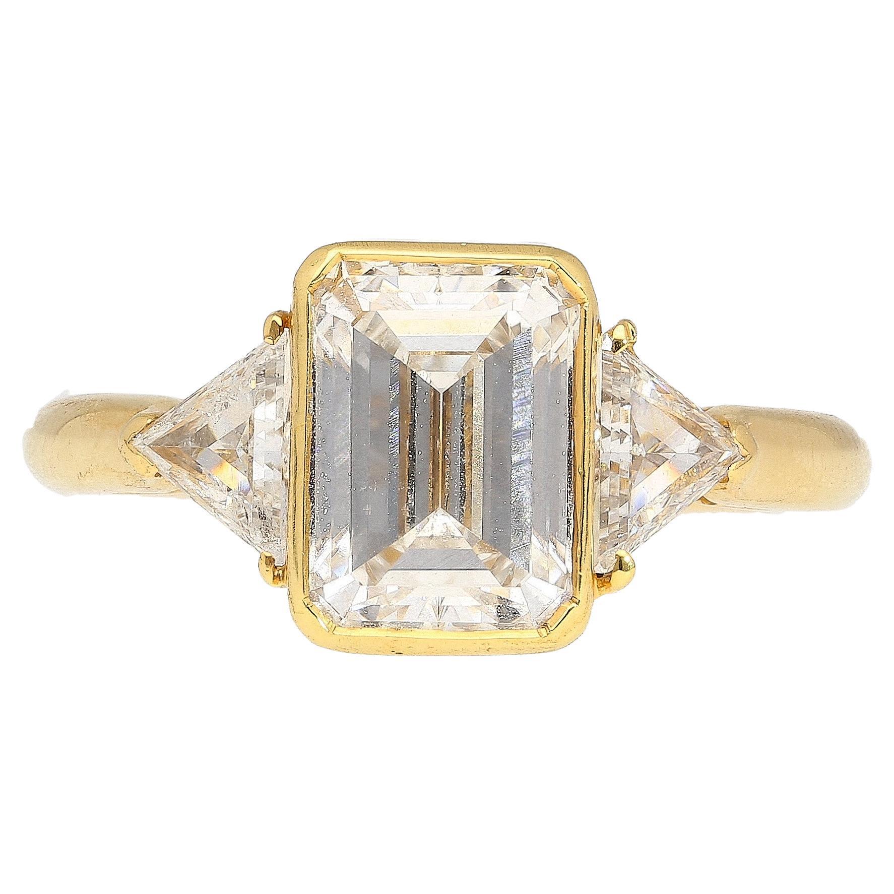 Boucheron signed three stone engagement ring, featuring an eye clean GIA certified 2.09 carat emerald cut E/SI1 diamond. Flanked by two trillion cut diamond side stones, all set in smooth 18K Yellow Gold.

The stone's SI1 clarity is unique in that