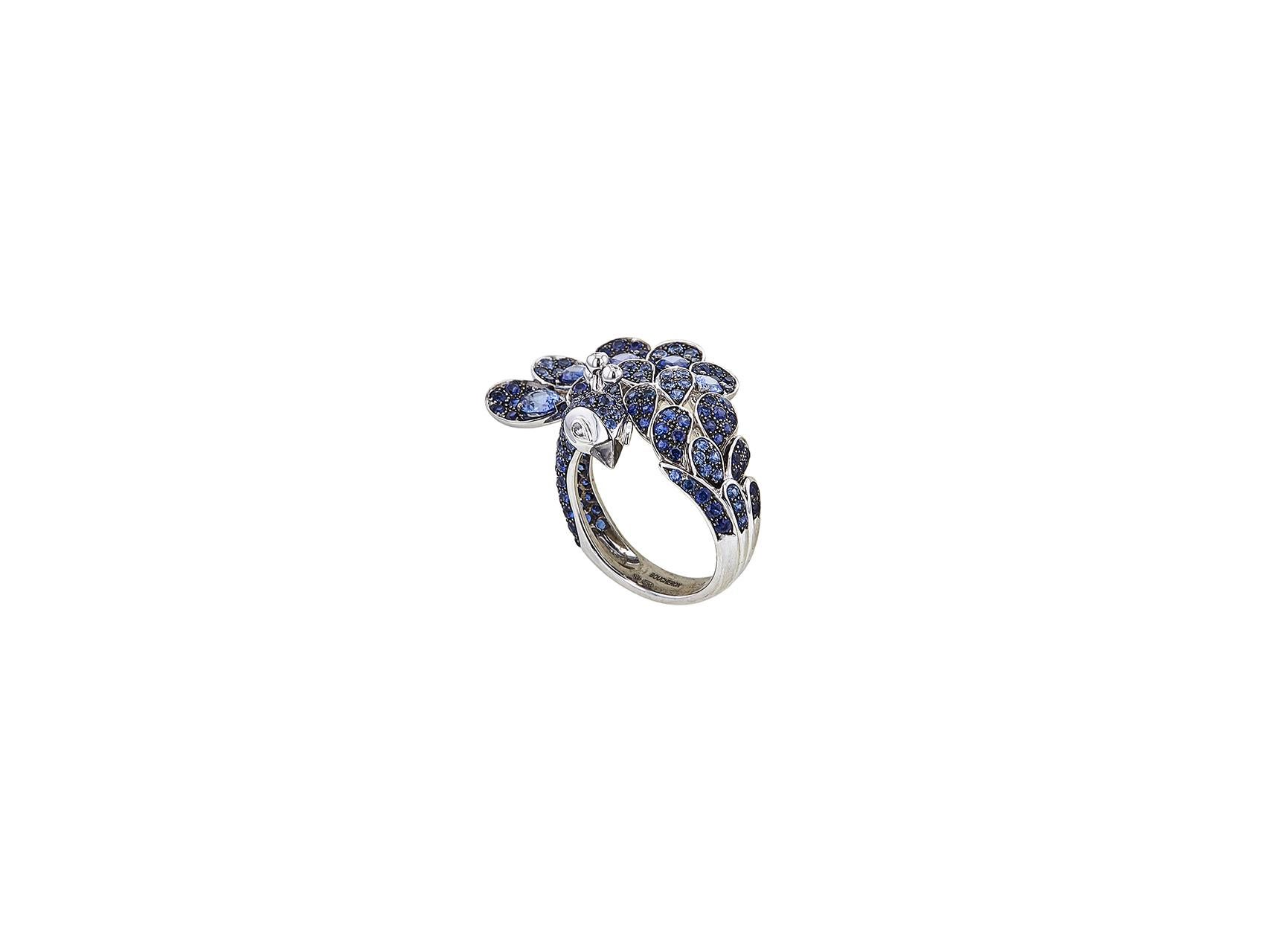 Authentic Boucheron Héra ring crafted in 18 karat white gold features a stunning peacock frame with pavé round and pear-shaped blue sapphires. The eyes of the peacock are comprised of pear-shaped diamonds with an estimated .15 total carat weight.