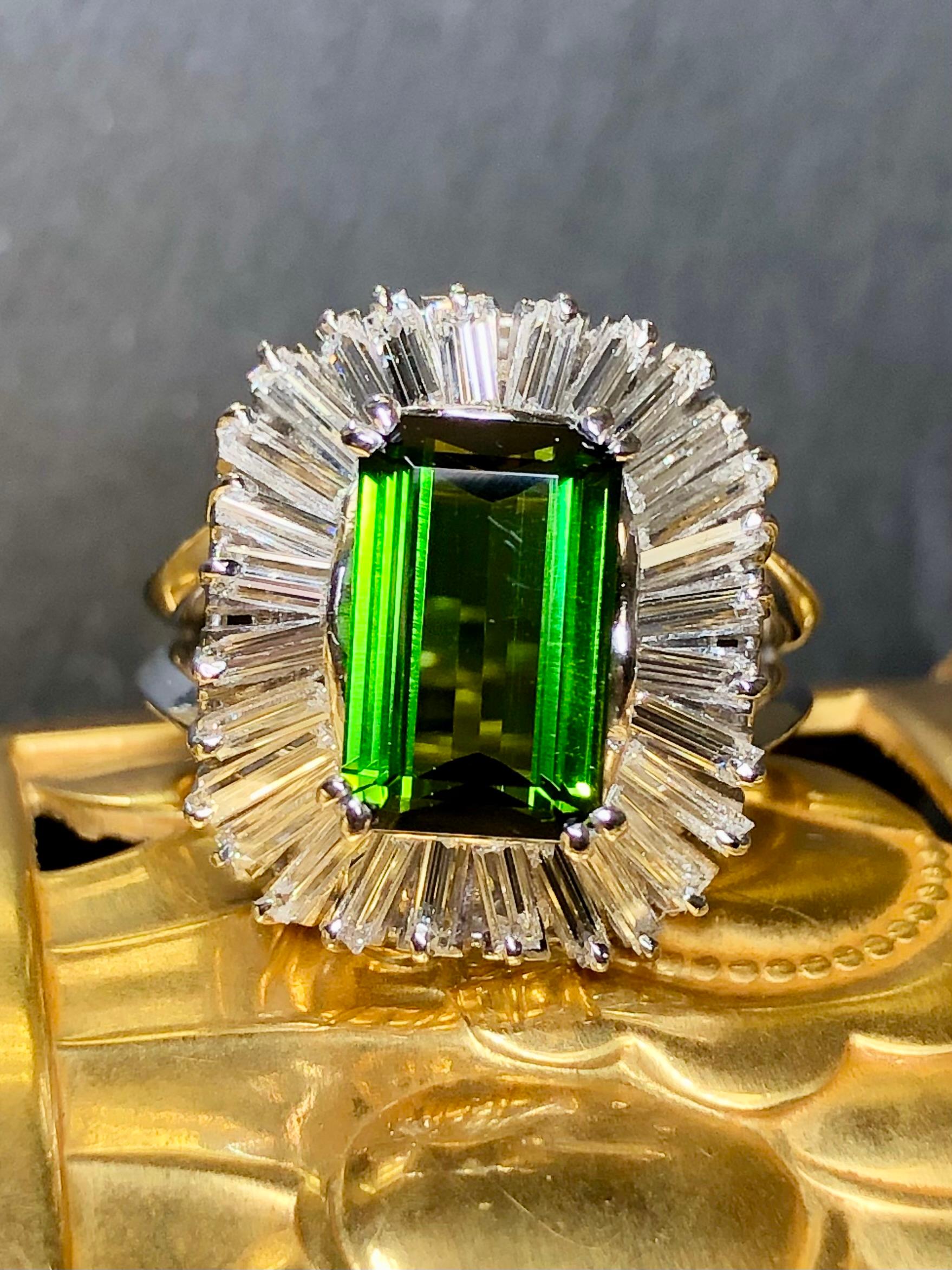 An exquisite ballerina style cocktail ring c. the 1960’s from the house of BOUCHERON. It is done in platinum and centered by an approximately 3ct deep green natural tourmaline surrounded by approximately 2.70cttw in F-G Vs1 clarity baguette