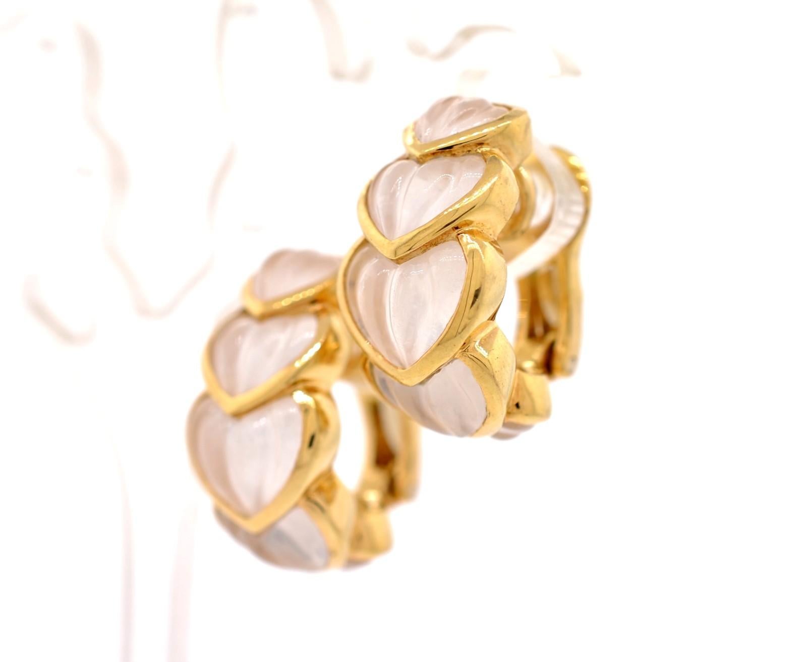 The French House of Boucheron has created these pretty and unusual natural Rock Crystal earrings. The 1/2 hoop designs each embrace 5 bezel-set carved heart-shaped rock crystals. The rich 18K yellow gold makes them stand out. With omega backs and