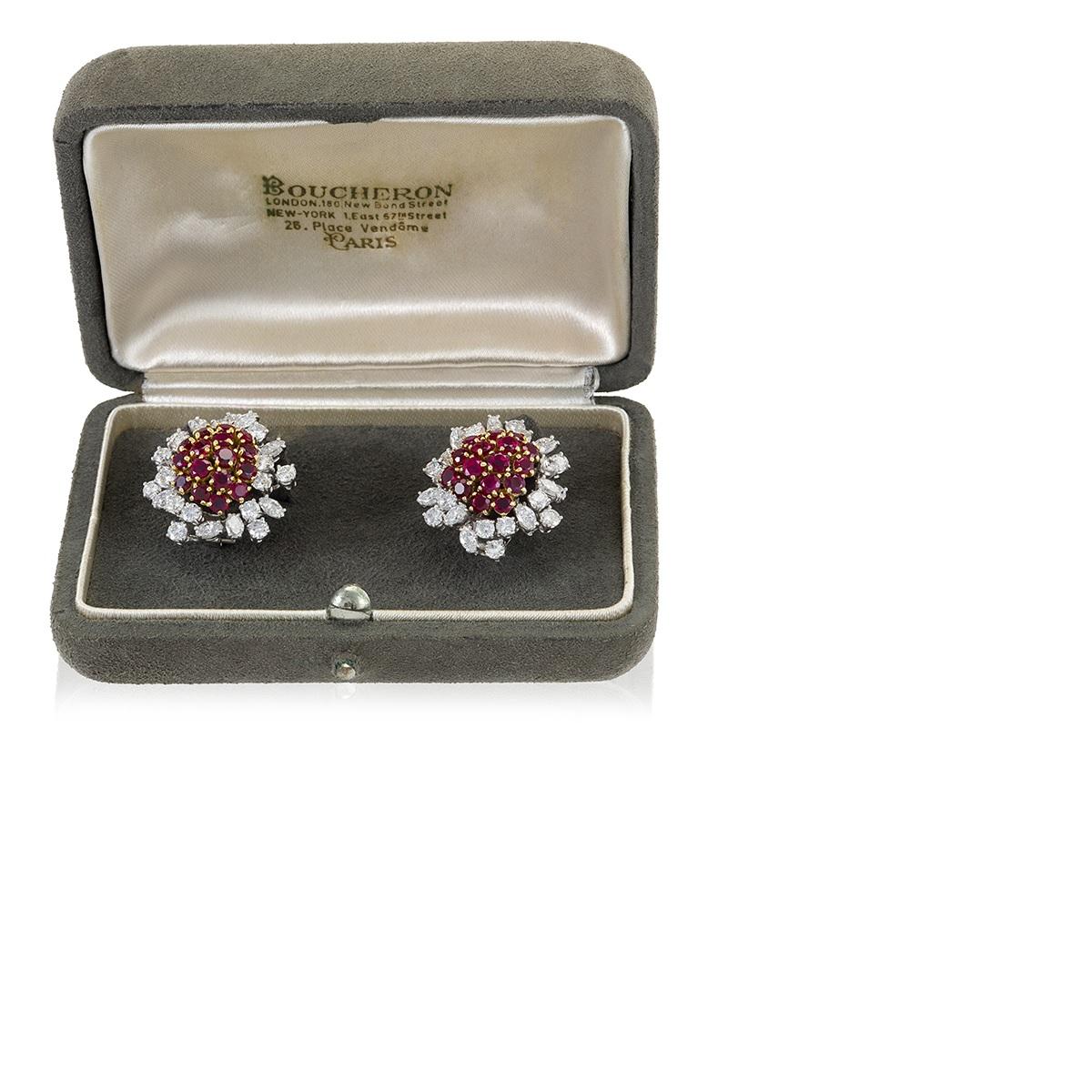 A pair of platinum- and gold-set diamond and ruby earrings by Boucheron. The earrings, housed in their original box from the mid-20th century, center on a semicircular raised cluster of 32 remarkably well matched rubies, total approximate weight