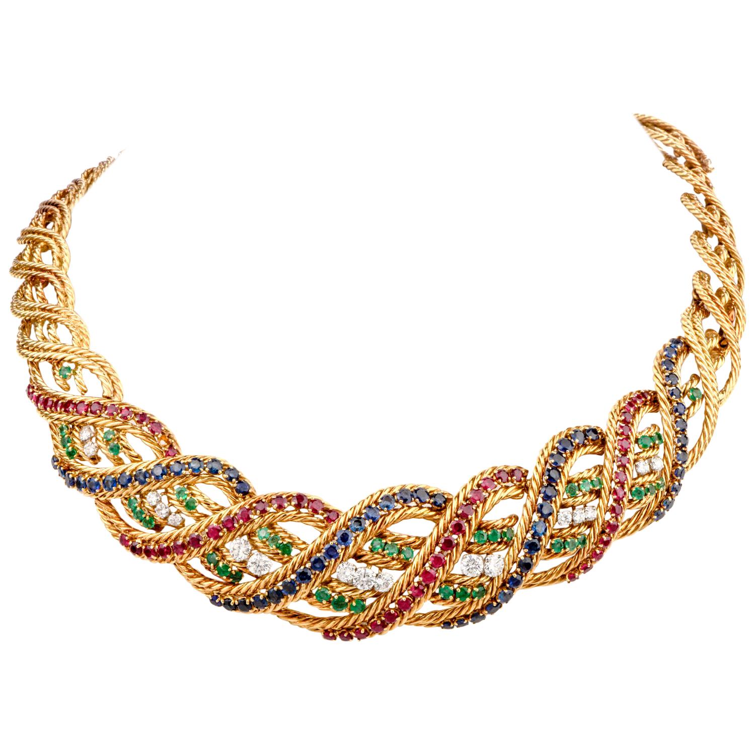 This stately vintage 1960-1970 French Boucheron Ensemble was created with a criss cross woven pattern and crafted in 18K gold. 

Neckalce:
Adorning the centermost part of this choker are round faceted Diamonds, Rubies, Emeralds and Sapphires.15