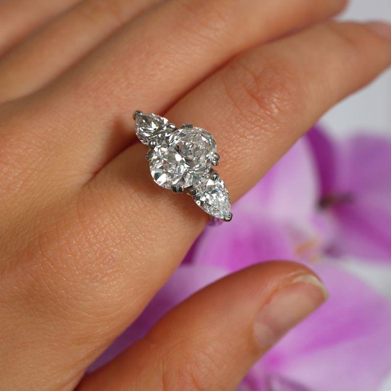 Bague en diamant Boucheron à trois pierres, avec au centre un diamant ovale de taille brillant pesant 3(10) carats, de couleur D et de pureté VS1, dans une monture fendue à quatre griffes. La pierre centrale est flanquée de diamants de taille