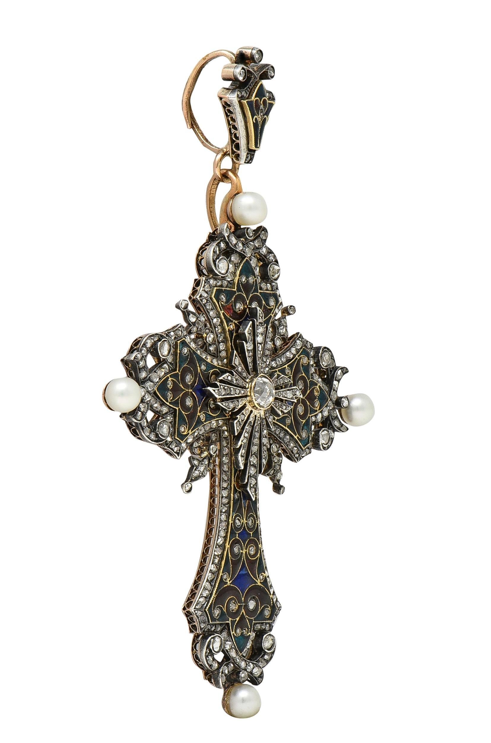 Designed as an ornate cross shaped form suspending from a fleur-de-lis shaped surmount
Comprised of flaring trefoil terminals with twisting edge surrounds and enamel throughout
Transparent medium red, green, and royal blue in color - quality