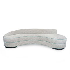 Divano moderno con sedile stretto e curvo, con bouclè neutro e imbottitura a contrasto