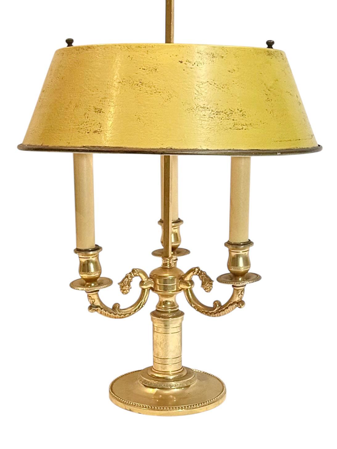 This is a vintage extremely high quality three lite French bouillotte lamp with tole shade and very high quality bronze shade is in the color yellow. The candle covers are papier-mâché. It was made in France around the late 1940s to early 1950s. The