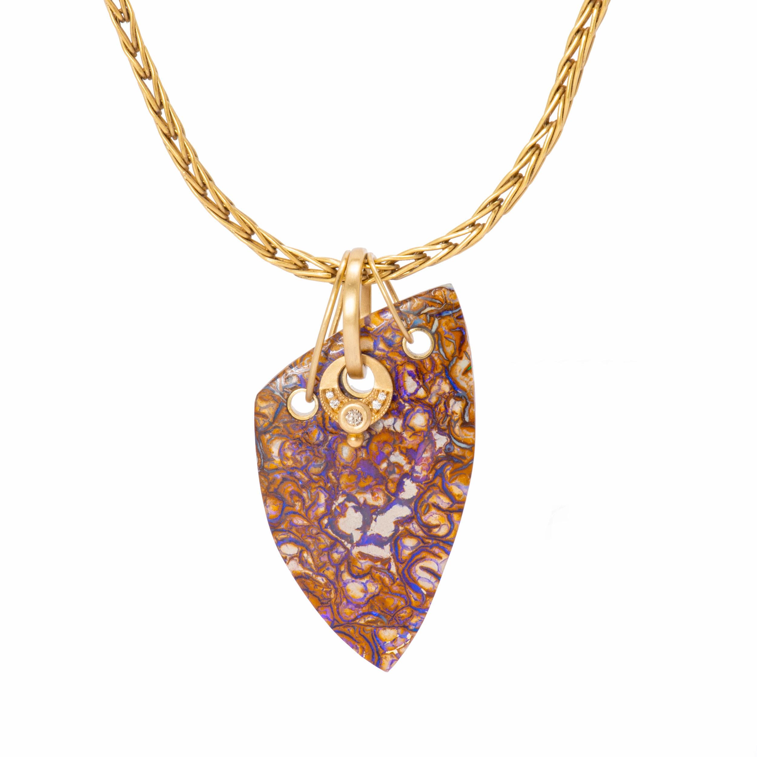 A rounded triangle slice of purple Boulder Opal sits behind a free hanging eclipse pendant of 18 karat gold set with white and cognac diamonds. A triad of 18 karat gold bails which are soldered as one add intrigue to a beautifully variegated slice