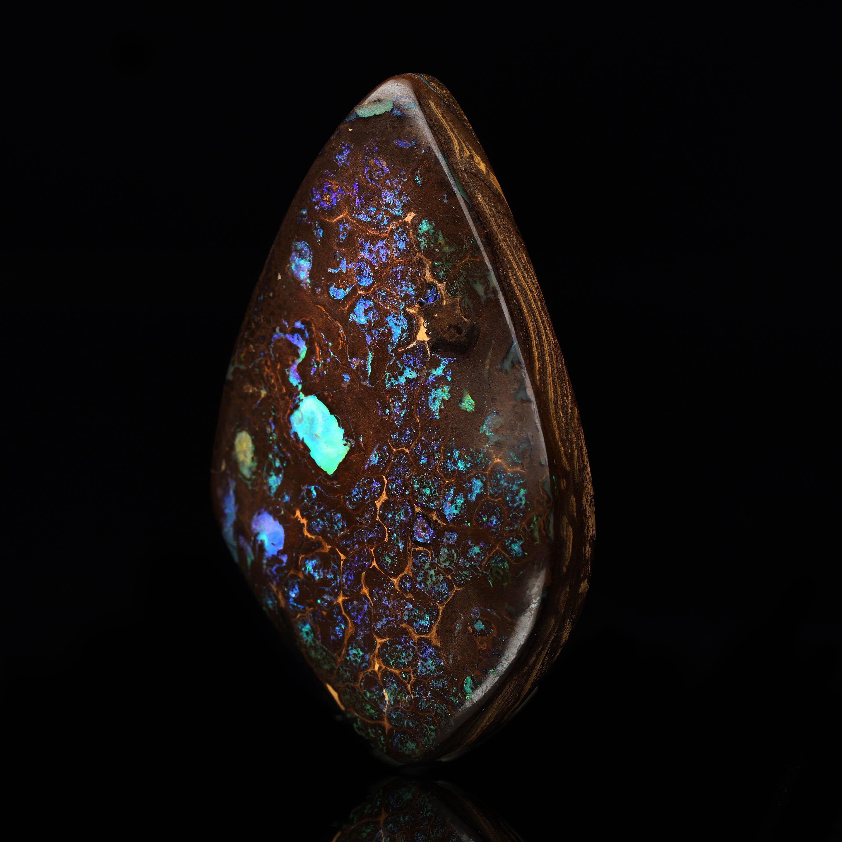 This magnificent Boulder Opal from Australia is a true masterpiece of nature, showcasing a breathtaking play of colors with deep blues, vibrant greens, and fiery oranges against a rich ironstone matrix. The opal's polished surface reveals intricate