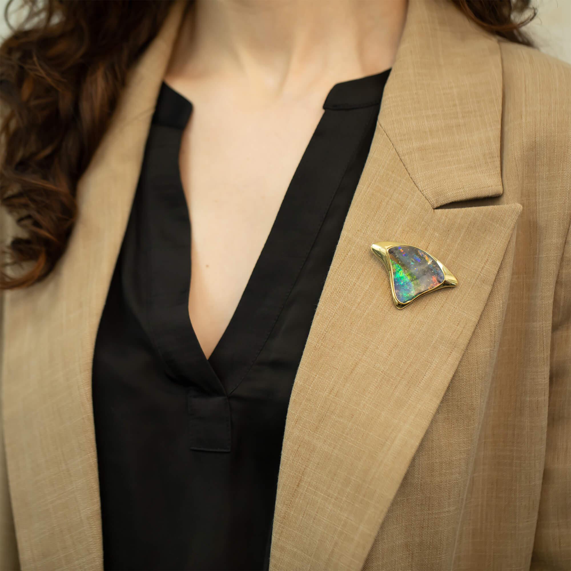 This unique, spectacular triangular brooch is set with one freeform solid Queensland boulder opal flat cabochon with two distinct bands of colour representing the nights sky and the sea. The opal is surrounded by a yellow gold custom mounting