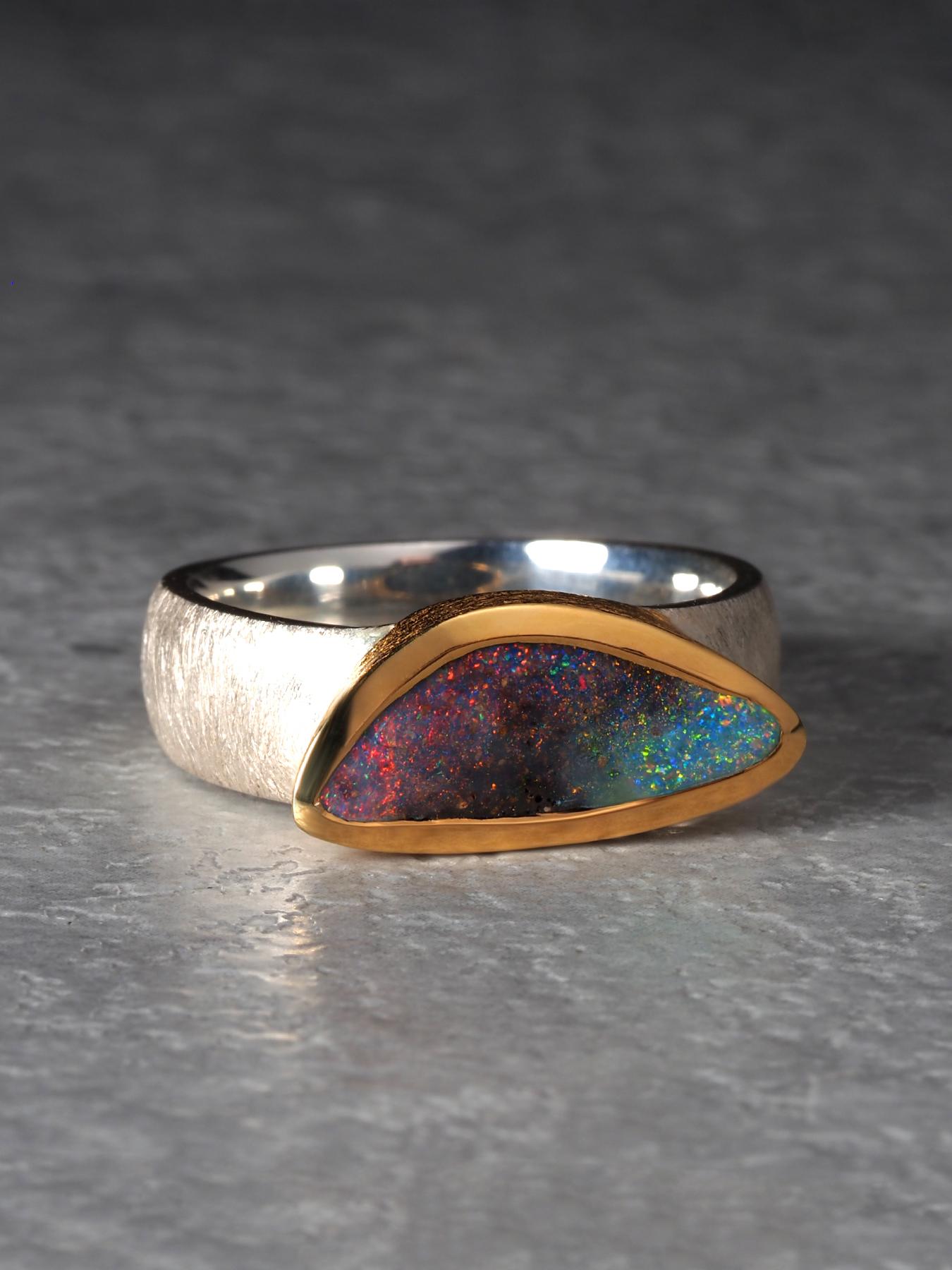 Questo elegante anello Boulder Opal è realizzato in argento massiccio 925 e oro 18 carati e presenta un'opale naturale di alta qualità proveniente dal Queensland, in Australia, rinomato per la produzione di pietre dall'eccezionale vivacità. L'opale