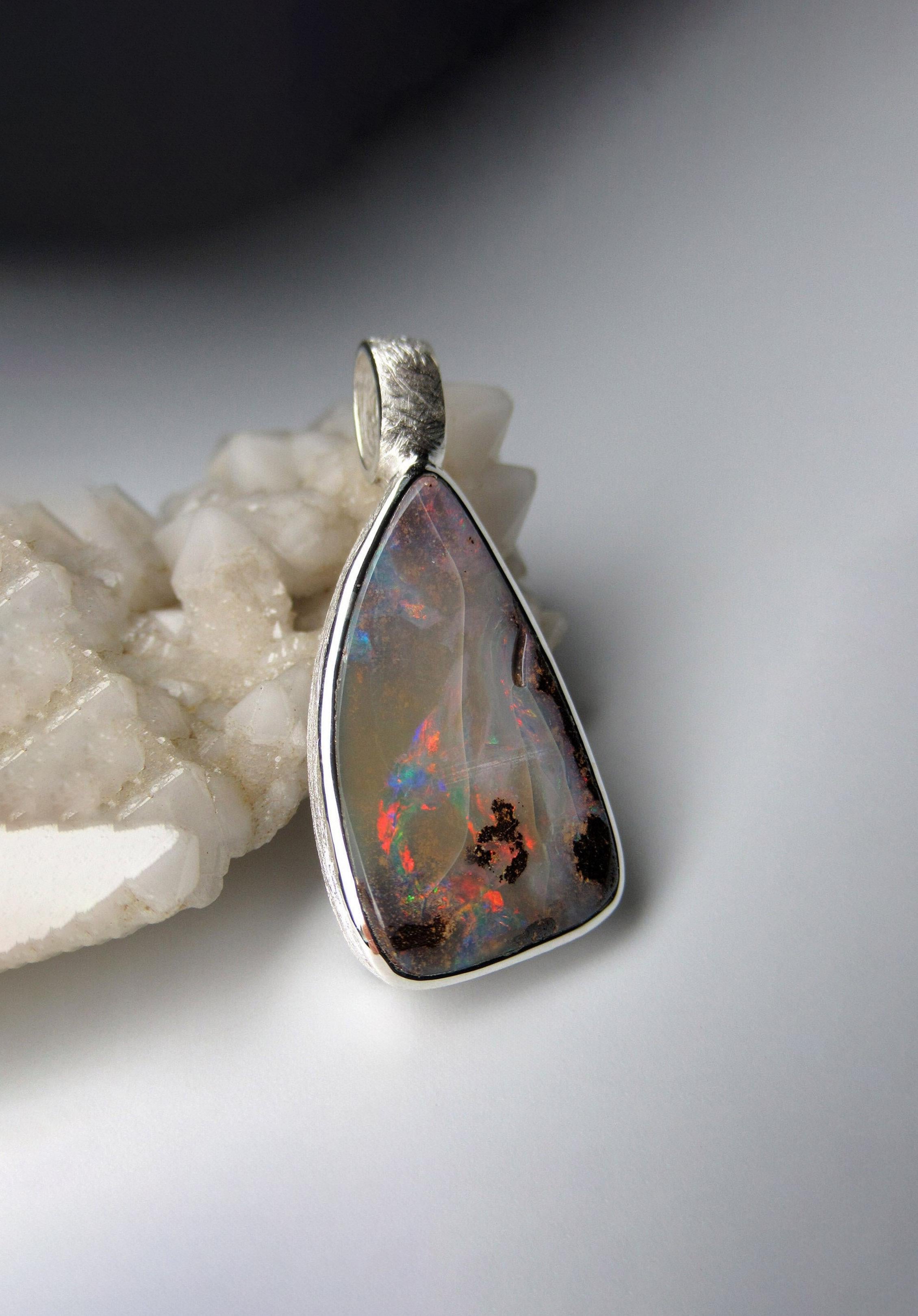 Boulder Opal pendant in matte finish silver 
gemstone origin - Australia
opal measurements - 0.16 x 0.55 x 0.98 in / 4 x 14 x 25 mm
opal weight - 11.25 carats
pendant length - 1.3 in / 33 mm
pendant  weight - 4.87 grams