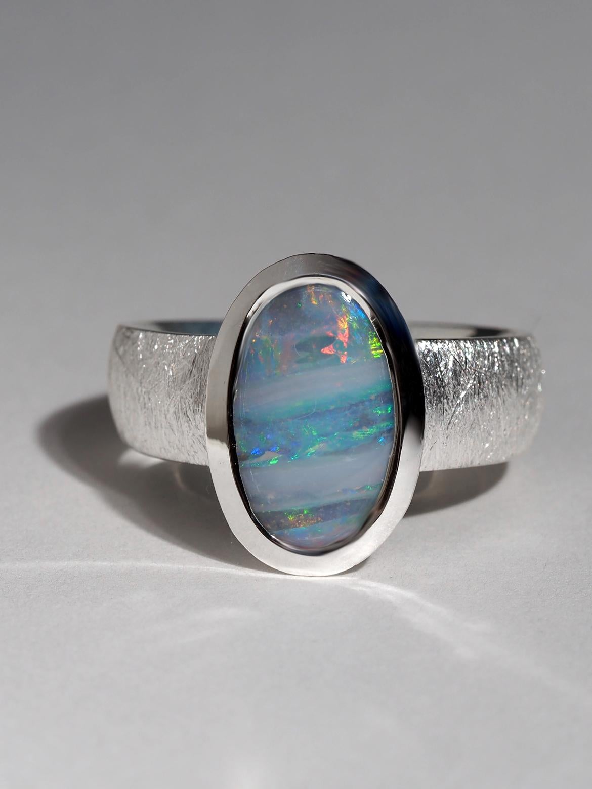 Este anillo de plata de ley presenta un elegante Ópalo de Boulder procedente de Australia, seleccionado por su refinado juego de colores y su forma naturalmente esculpida. El ópalo muestra tonos característicos de azul, verde y rojo cálido,