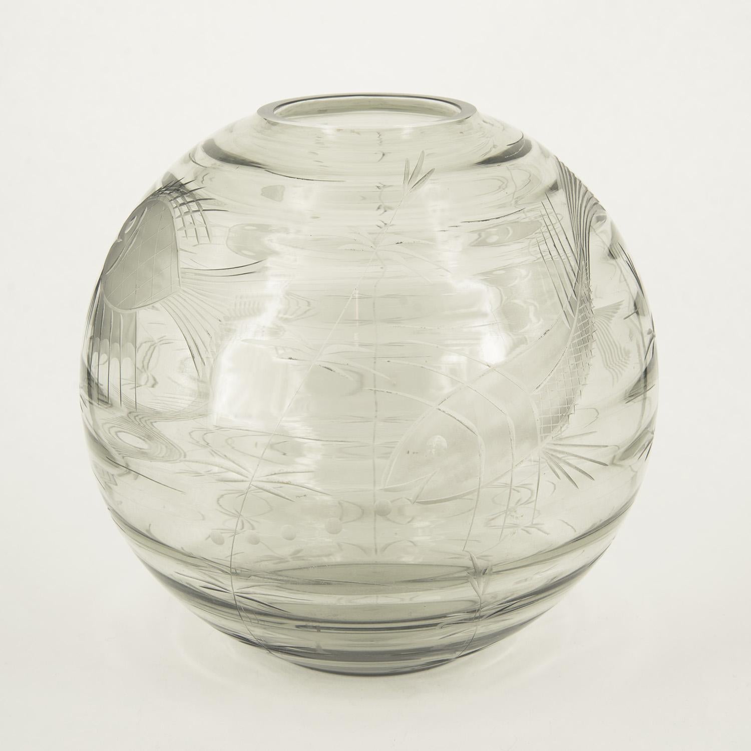 Un vase inhabituel en verre de Murano incolore gravé de motifs marins, dont la forme sphérique rappelle la boule des poissons rouges. La riche décoration est obtenue par la gravure à la roue, réalisée par S.A.L.I.R. au tournant des années 1930 et