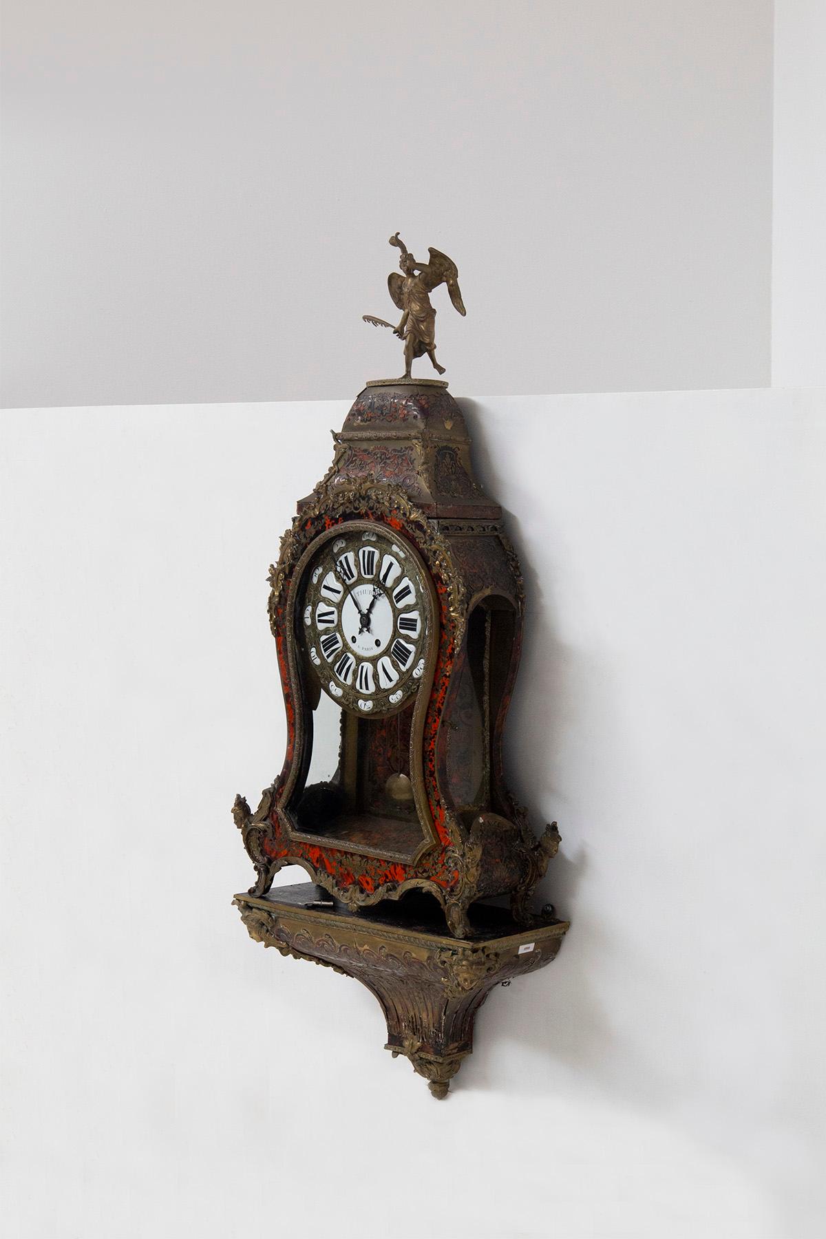 Frühe 1900's Französisch Boulle Uhr. Dieser exquisite Zeitmesser, ein wahres Meisterwerk der Handwerkskunst, ist eine Symphonie aus gemeißelter und vergoldeter Bronze, verziert mit dem Reichtum einer Schildpatt-Imitation und verziert mit