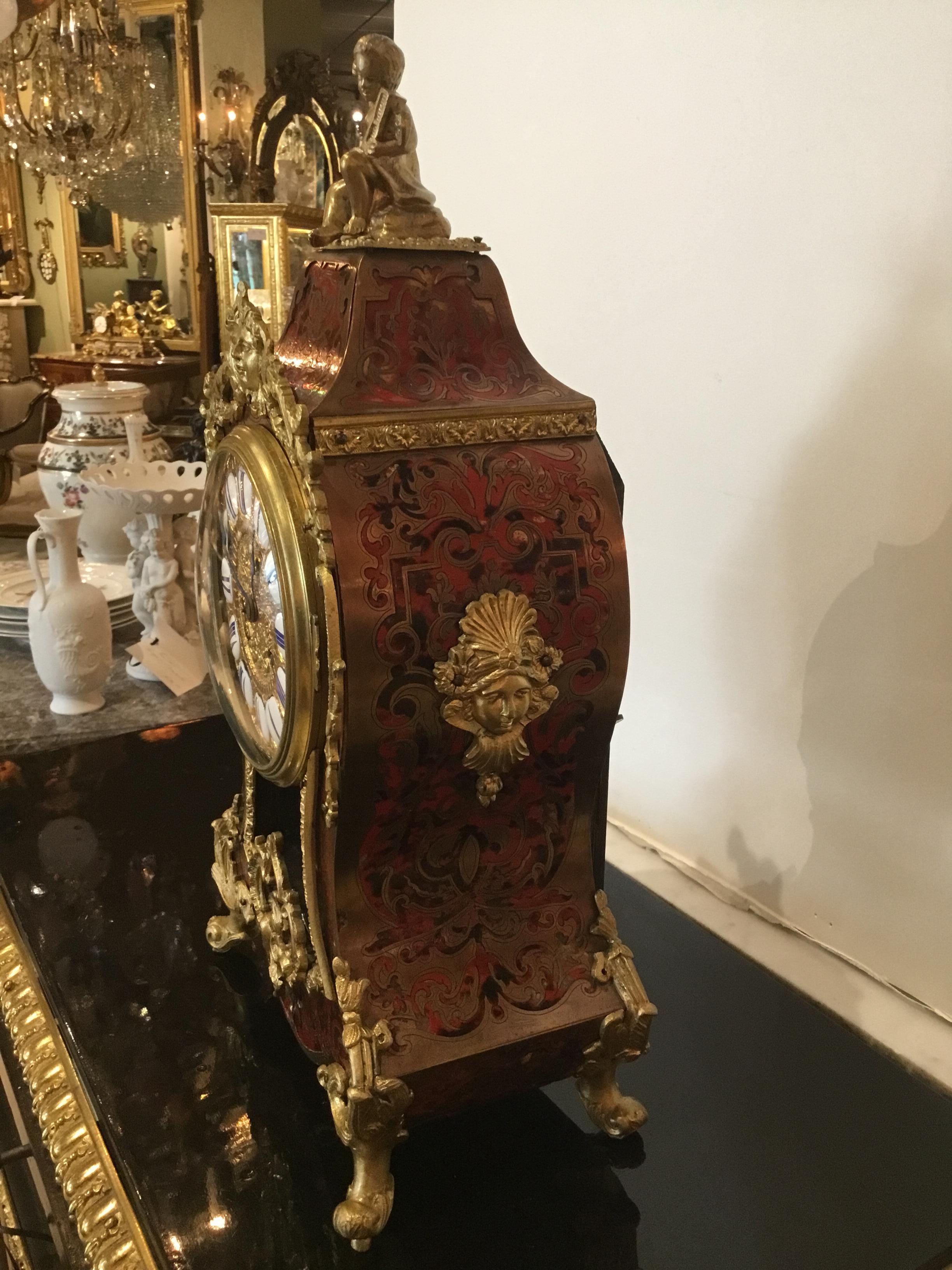 Late 19th century, a Louis XIV style bracket clock, the rectangular crest
Surmounted by a seated putto on a balloon form case with a gilt maiden’s
Mask suspending acanthus and laurel detailed mounts, over a glazed
Molding bezel opening to a