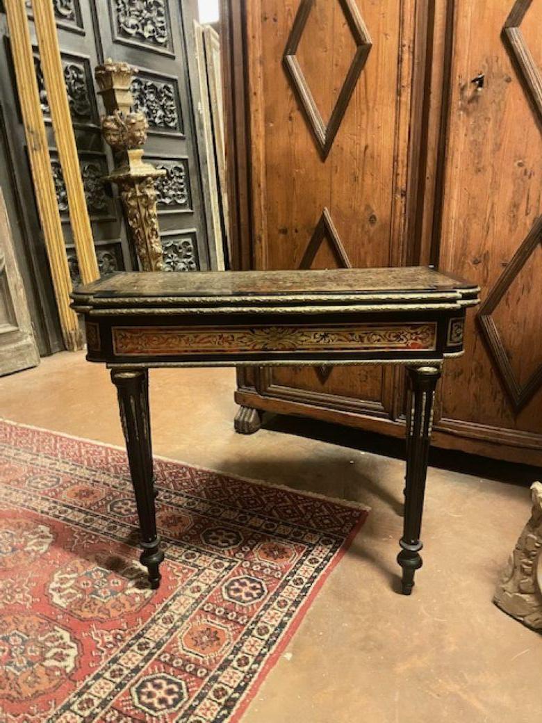 Antique Boulle style game table, made of mixed woods such as ebony and rosewood, in darkened ebonized wood and gilded decorations, Book-like opening top, with brass inlays. The legs are fluted truncated pyramids.
Original from the second half of the