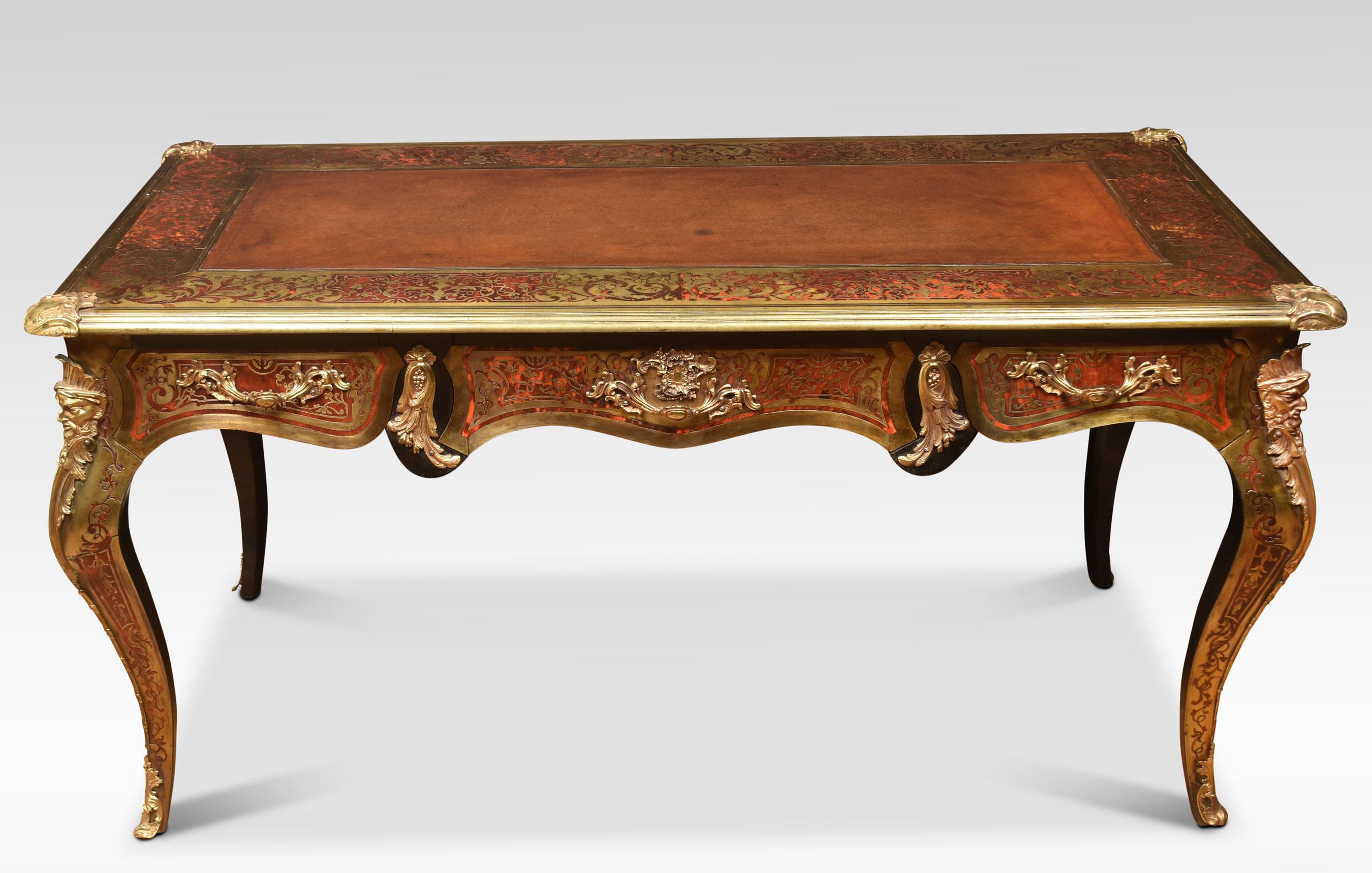 A fine Régence style Bureau plat in the Manner of André-Charles Boulle, inlaid all over with intricate brass embellishments on a red tortoiseshell ground and having ornate gilt metal mounts. The rectangular top with an engraved brass border