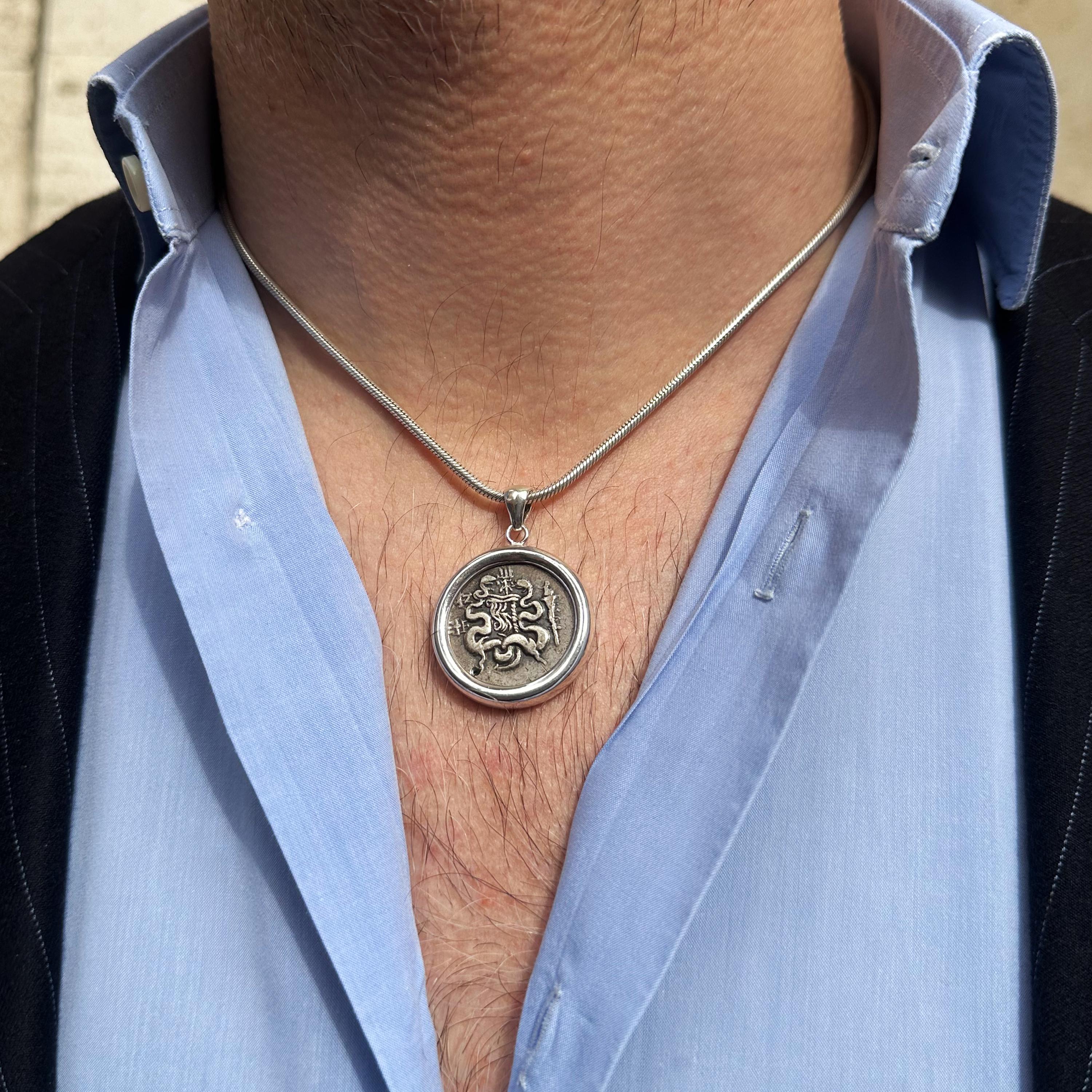 Découvrez un authentique pendentif en monnaie romaine datant de 82 av. J.-C., représentant au recto un arc avec une flèche entre deux serpents enroulés et au verso une ciste mystique. Cette pièce remarquable a été frappée à Pergame, comme