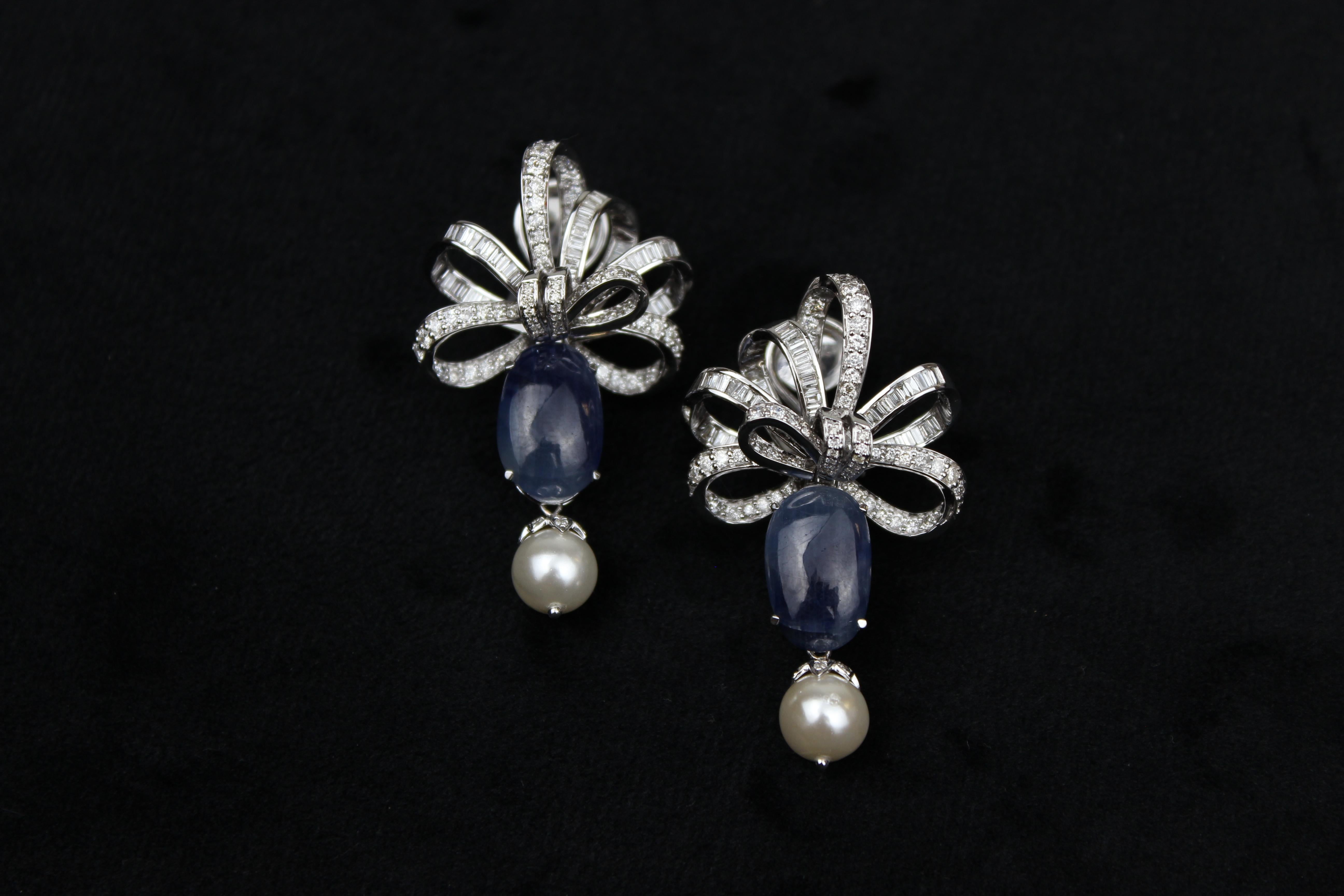 The earrings have a classic and timeless design that showcases the beautiful blue sapphire gemstones and the dangling pearls. The bow design adds a touch of femininity and elegance to the overall look of the earrings, creating a unique and