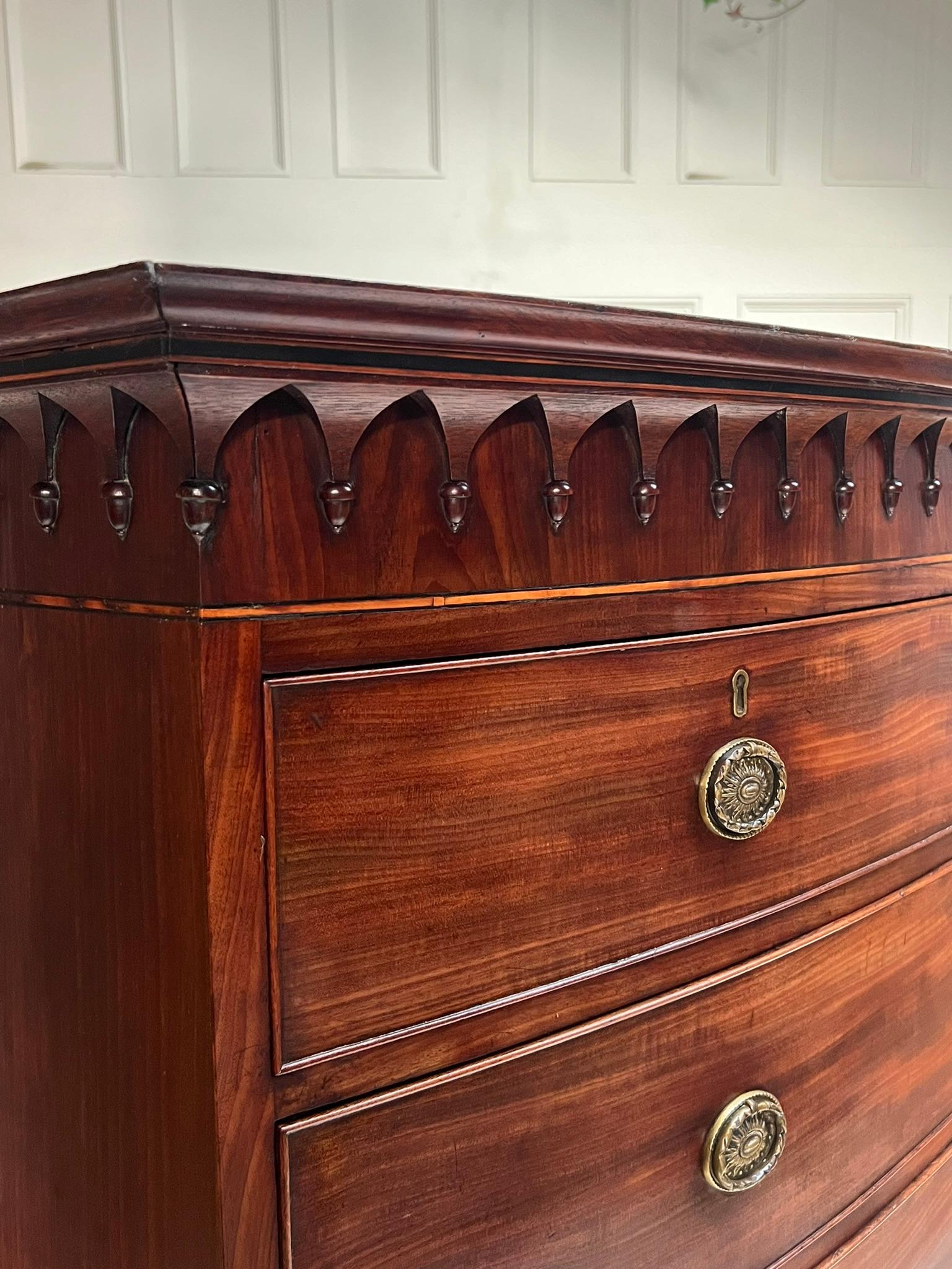Regency period bow front tallboy chest on chest.

The top chest boasts a detailed arcaded gothic cornice above an ebony and boxwood stringing and a 2 over 3 configuration.

The base contains a brushing slide with 3 lower drawers above splayed feet