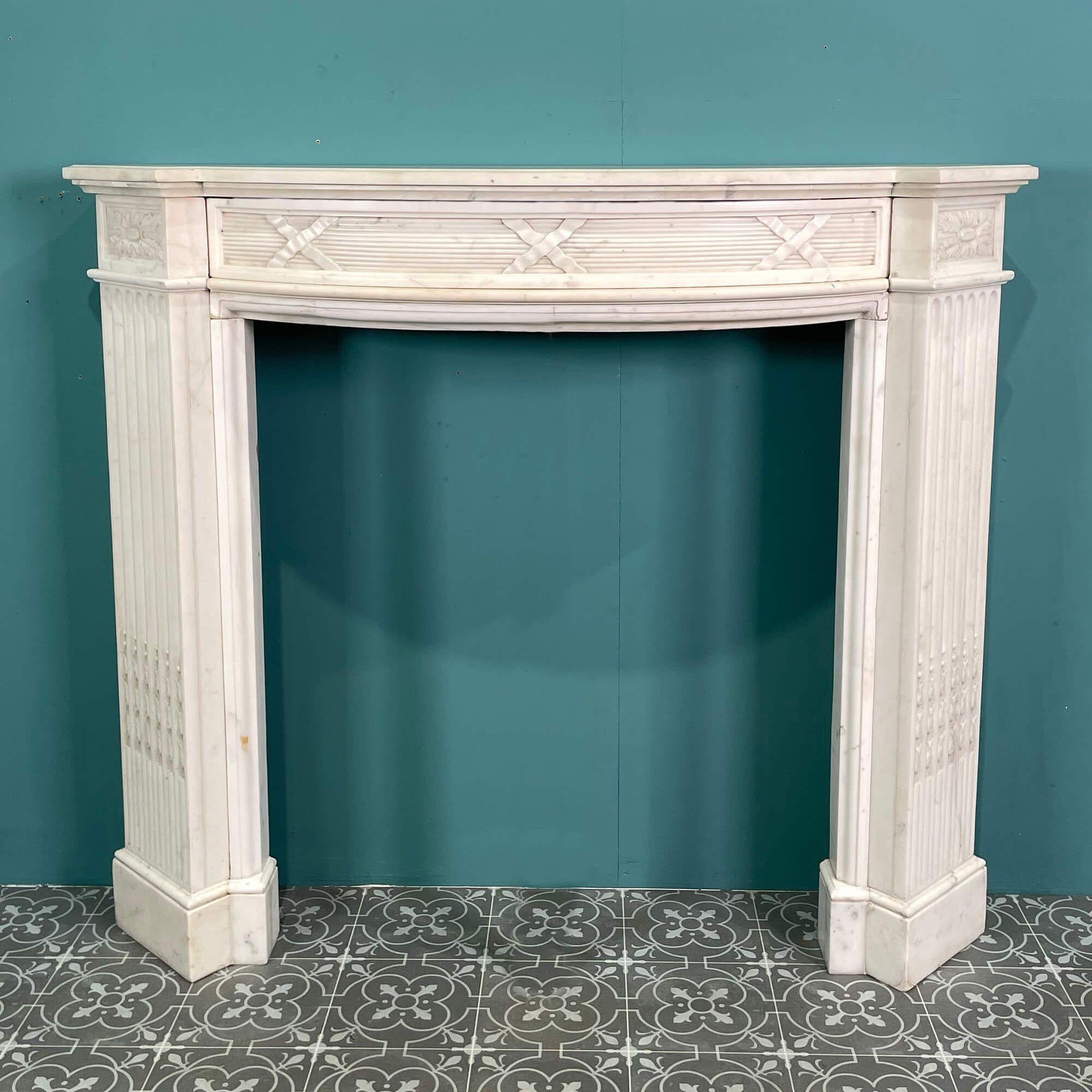 This stunning antique white marble fire mantel dates from the mid 1800s. Made entirely from statuary white marble, it is petite in scale with a curved bowfront rarely seen in antique fireplaces of this era. A mix of styles is present, showcasing