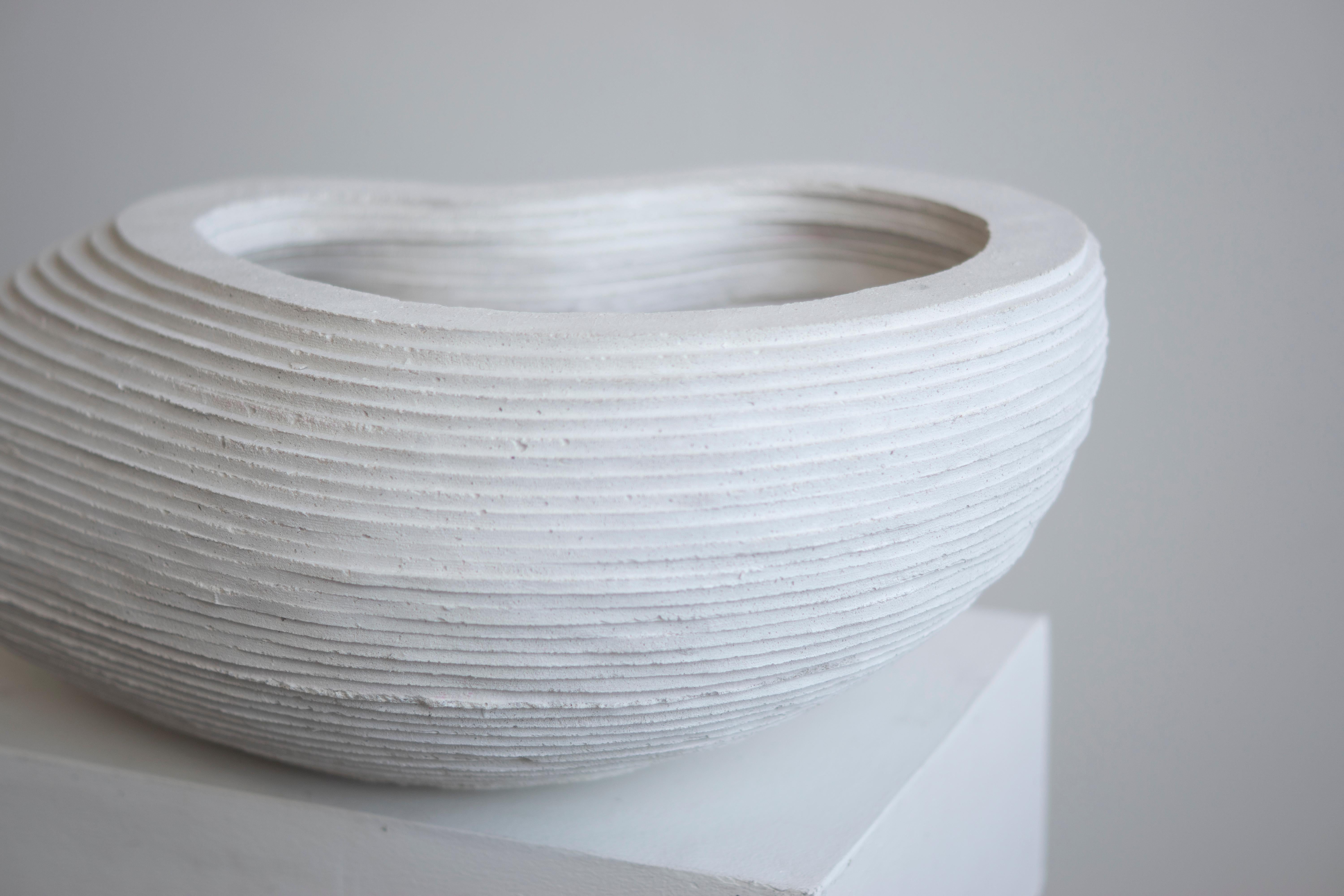 White hand-cast bowl for indoor and outdoor use.

At the intersection of art, craft, and design, Concrete Poetics' debut collection of hand-cast cement sculptural furniture and accessories streamlines visually intriguing and dynamic forms