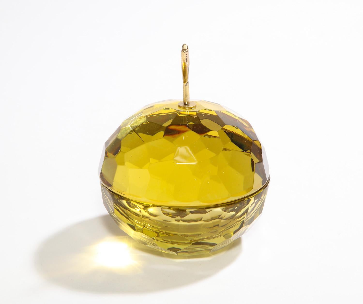 Covered bowl by Ghiró Studio. Studio-made covered bowl of hand carved glass. Brilliant-yellow colored glass featuring faceted exterior and all polished edges. Cast-brass handle and artist signed underneath.