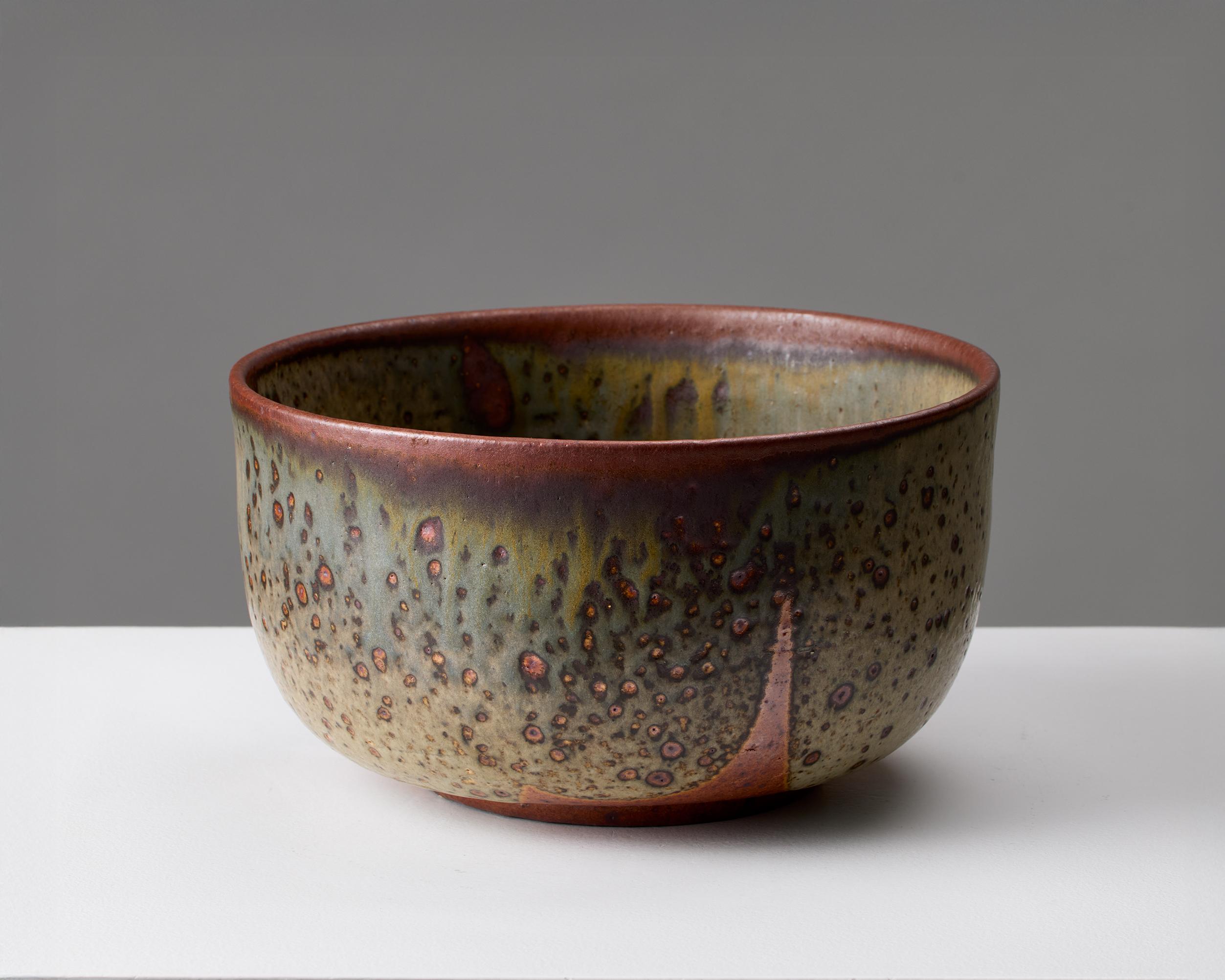 Este cuenco de cerámica del alfarero sueco Rolf Palm ejemplifica el refinado arte que define el diseño cerámico escandinavo de mediados del siglo XX. Realizada a mano y firmada por el artista, la pieza muestra la característica paleta de esmaltes