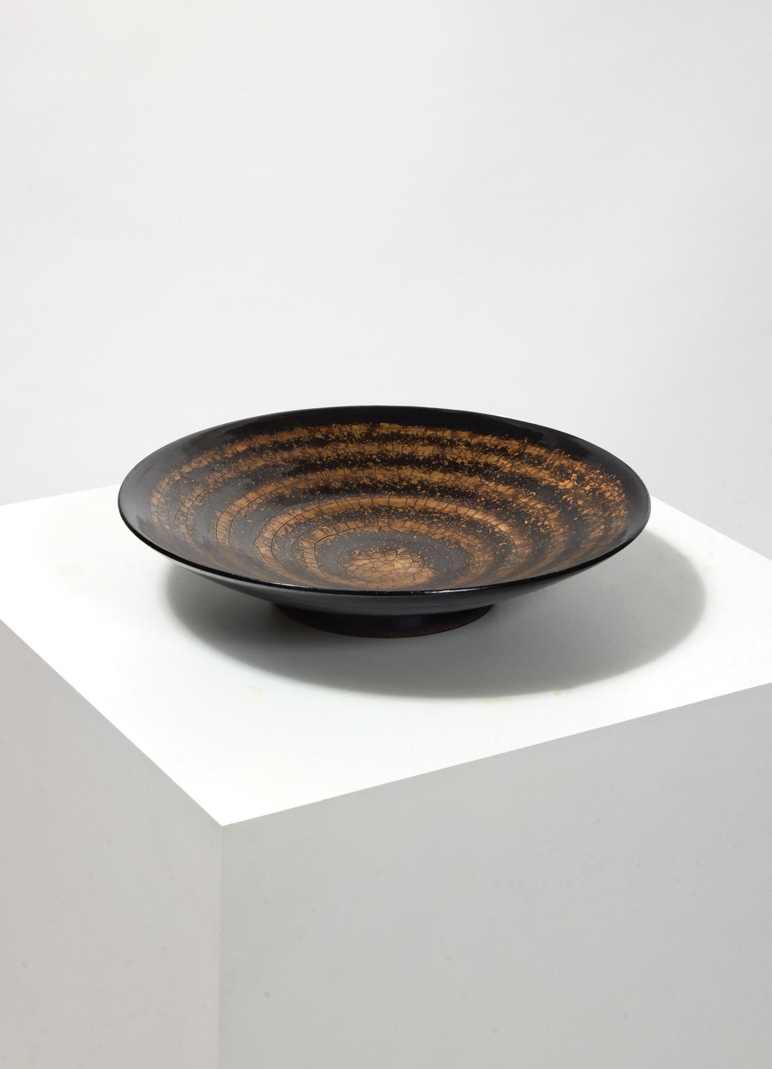 Ceramic bowl with black enamel and spiral pattern drawn in cracked gold.

Signed under the base 