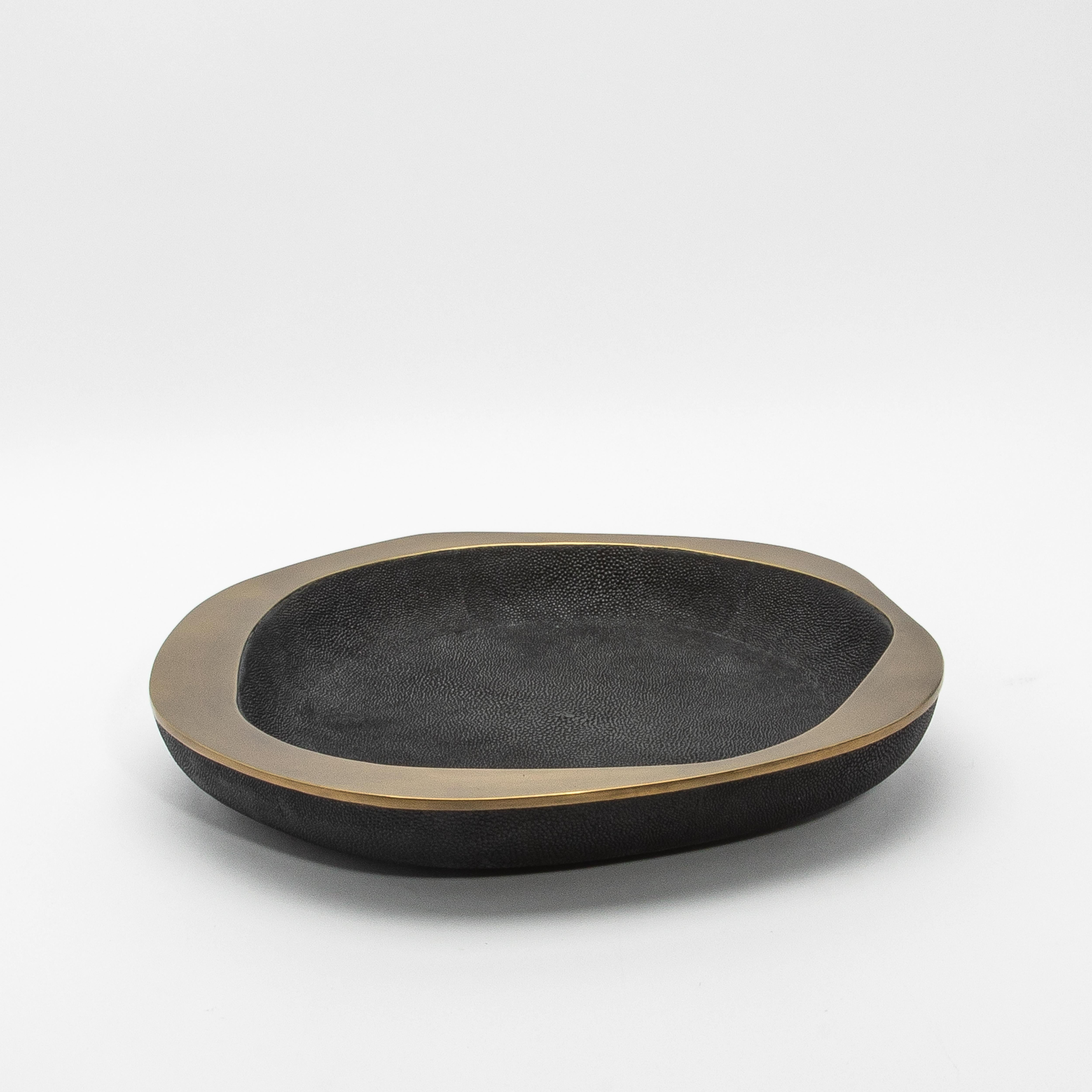 The Lily Bowl in black shagreen with brass details by R&Y Augousti exudes refined elegance through its striking contrast of luxurious materials. Handcrafted from the finest black shagreen, the textured surface adds depth and richness, while the