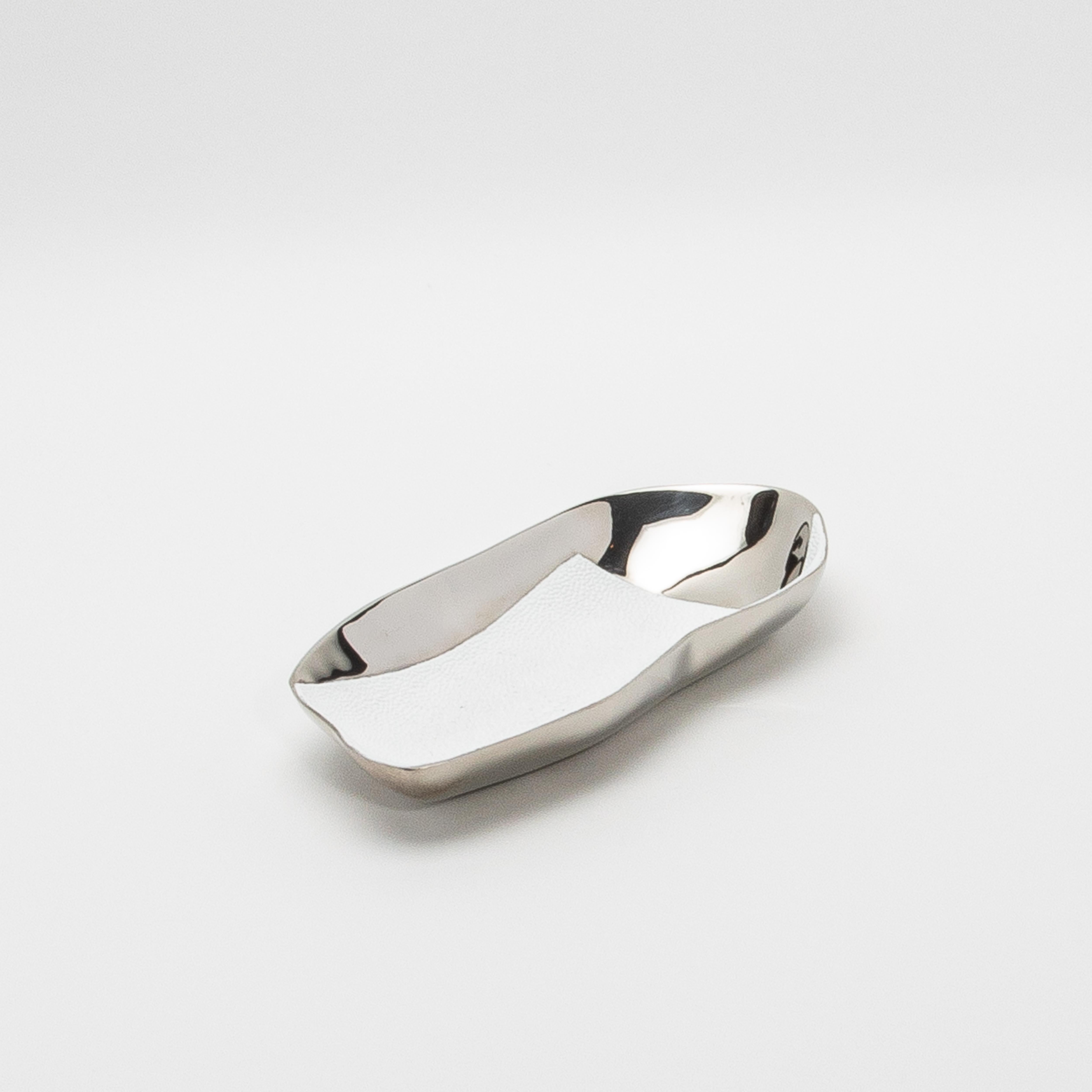 The Chital bowl by Kifu Paris is a stunning masterpiece, crafted from premium materials that exude sophistication and refinement. This hand-crafted bowl combines the elegance of white shagreen with the sleek, mirror-like finish of polished stainless