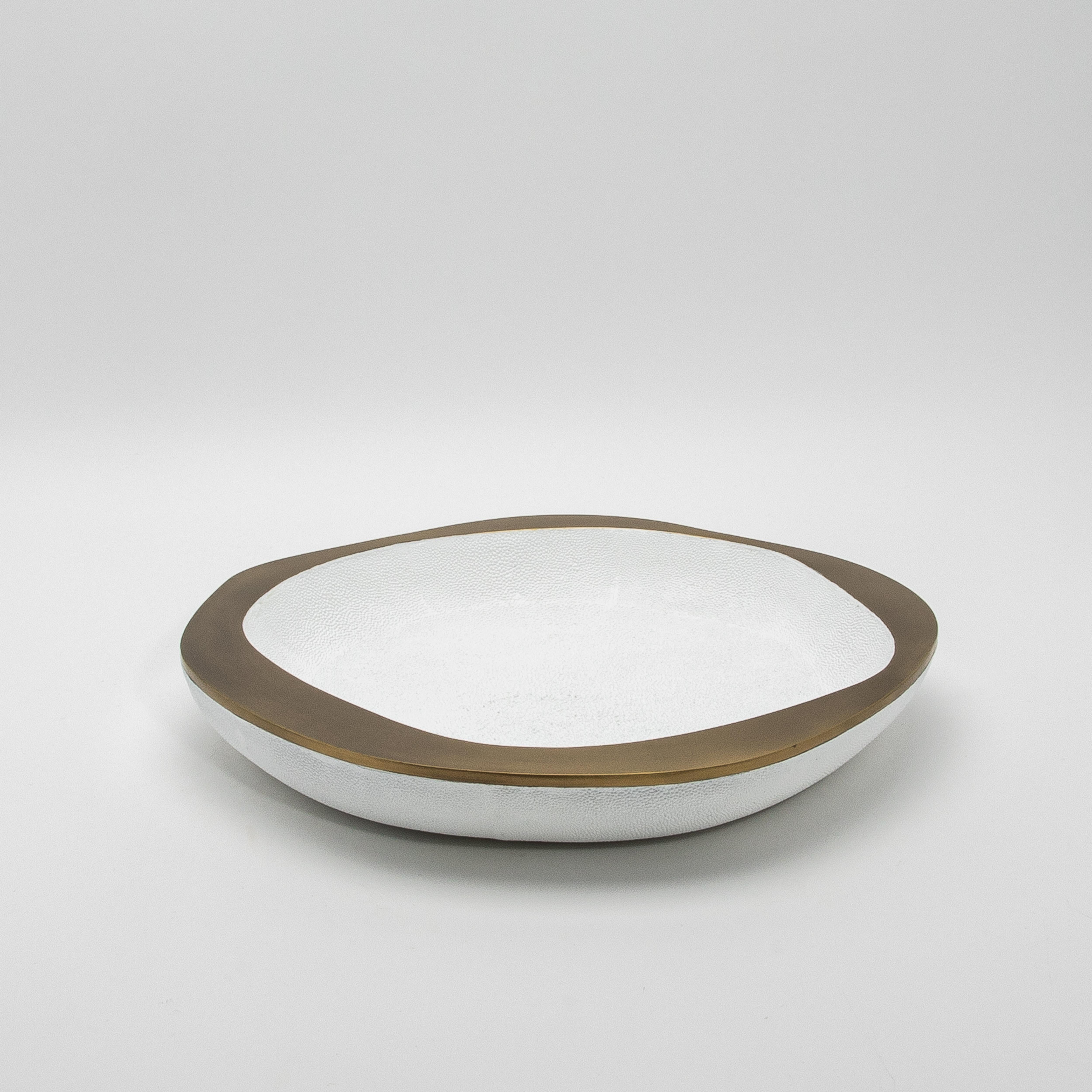 Le bol Lily en galuchat blanc avec détails en laiton patiné bronze de R&Y Augousti dégage une élégance raffinée grâce à son contraste saisissant de matériaux luxueux. Fabriquée à la main à partir du plus beau galuchat blanc, la surface texturée