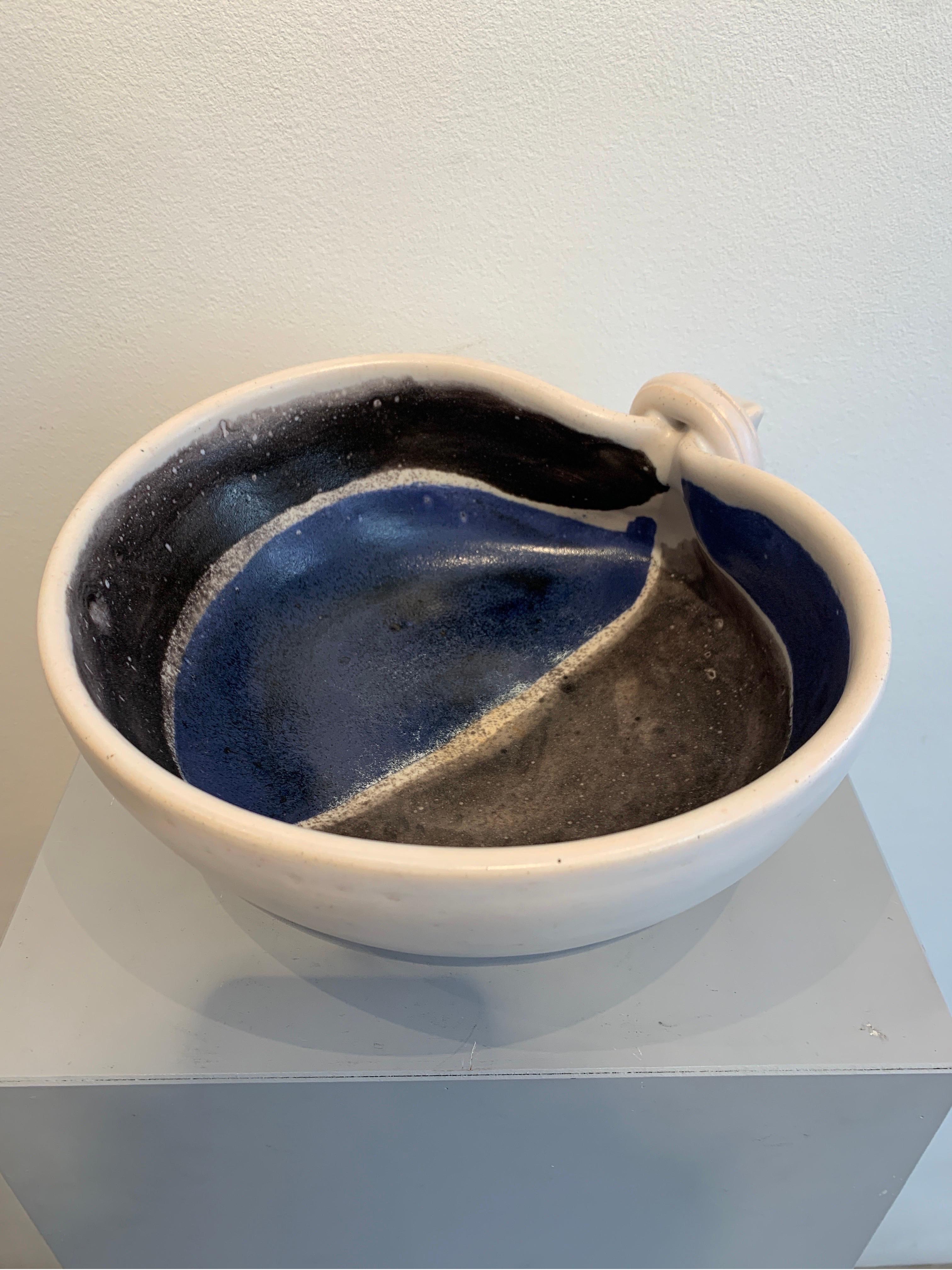 Mado Jolain ist ein renommierter französischer Keramiker, der in den 1950er Jahren tätig war. Die vorliegende Vase ist aus Steingut gefertigt und cremefarben emailliert. Das Dekor ist eine Abstraktion in Schwarz- und Blautönen. Sie gilt als einer